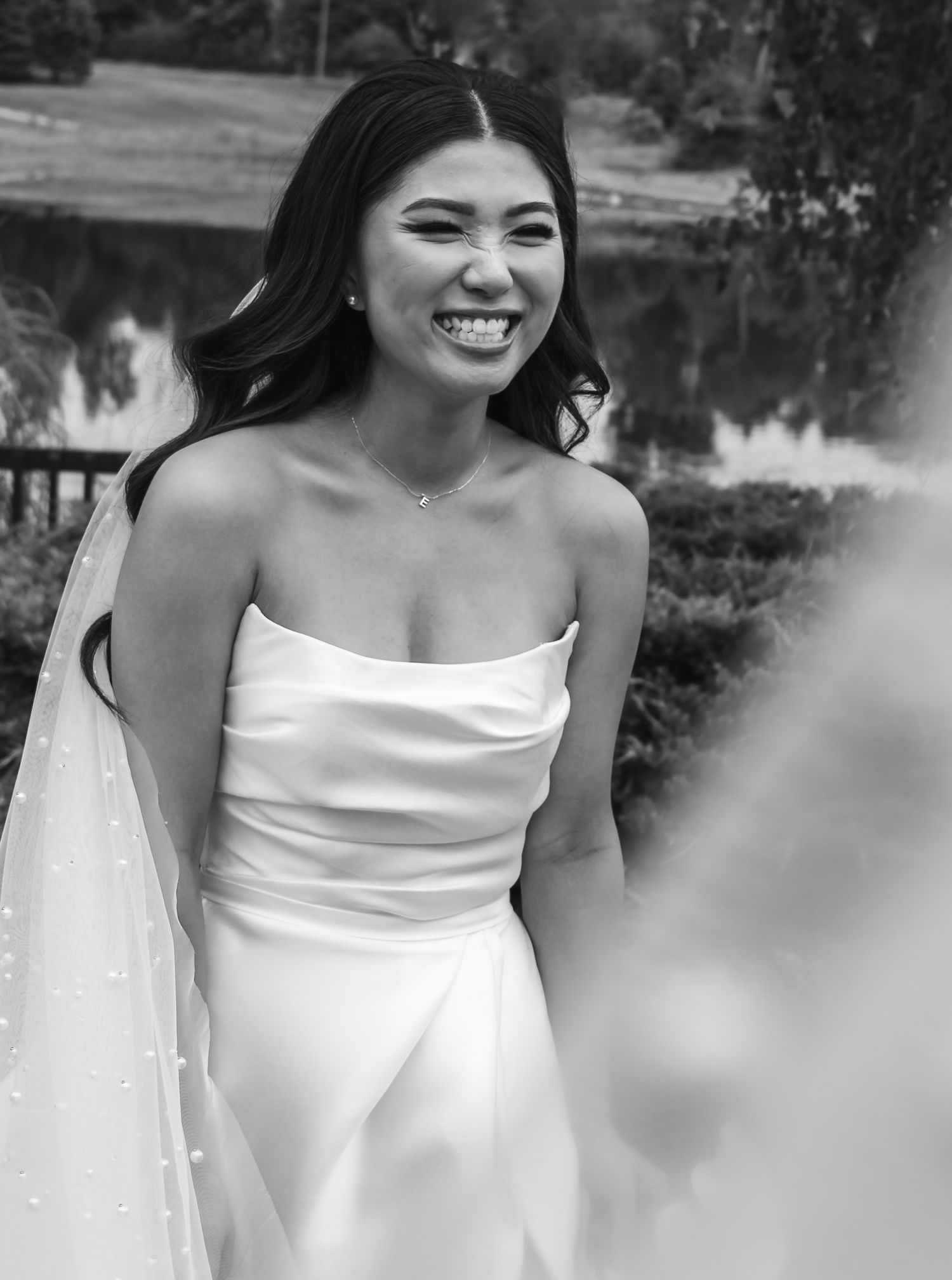 A joyful moment captured in black and white of a bride wearing a strapless white wedding gown.
