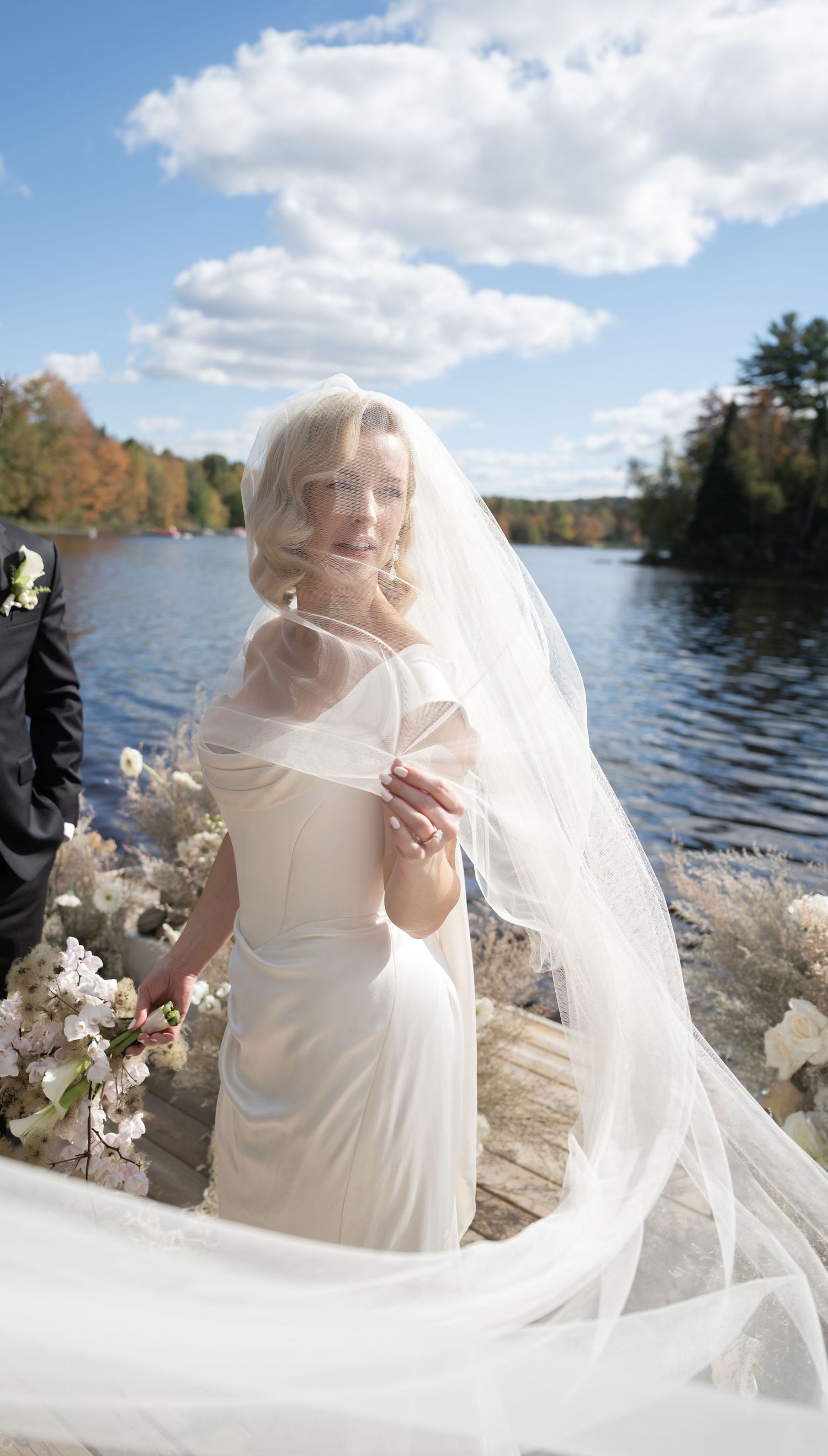 Ethereal bridal portrait by lakeside with flowing veil catching sunlight.