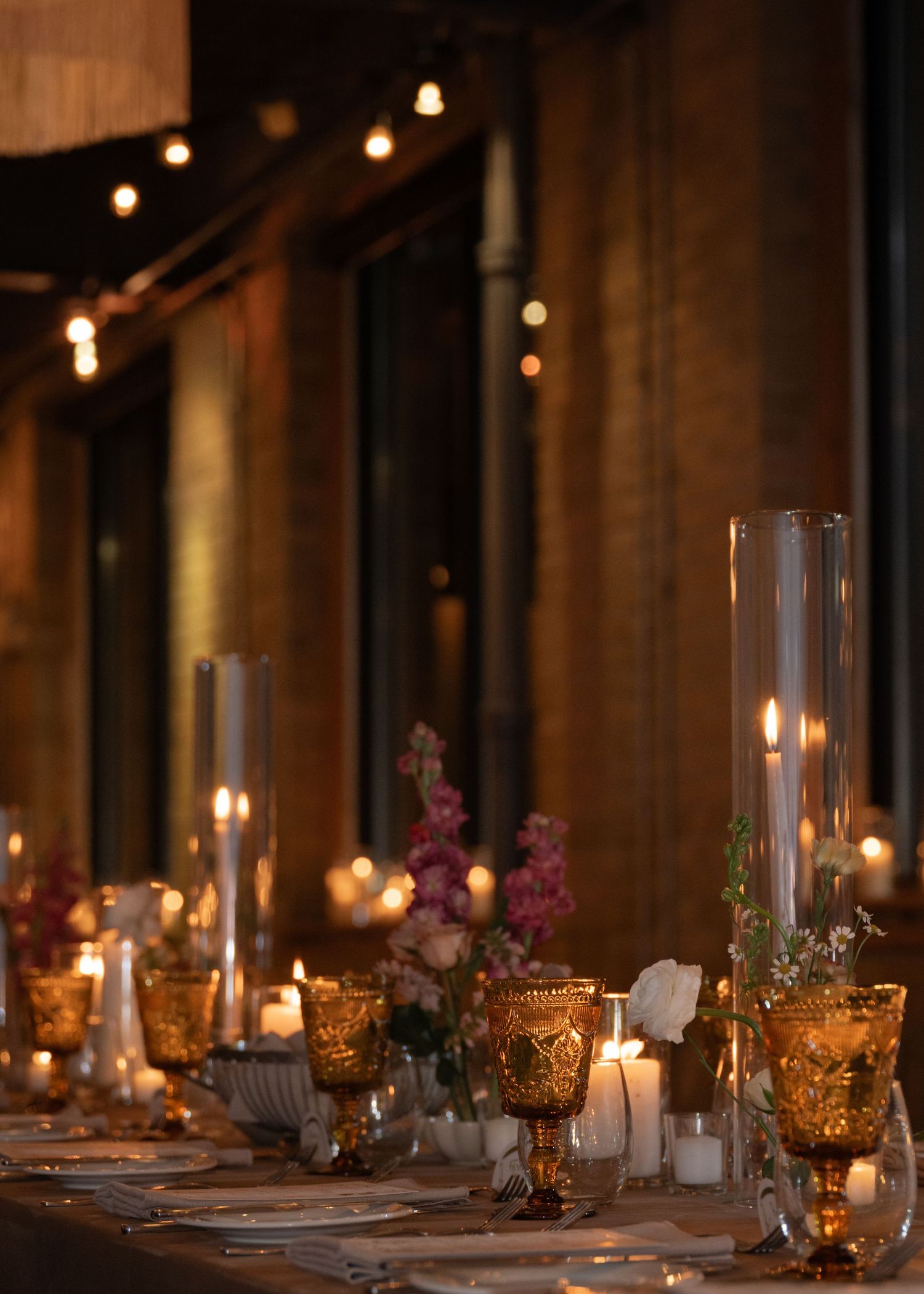 Elegant wedding reception table with gold votives and glass candleholders creating romantic ambiance.