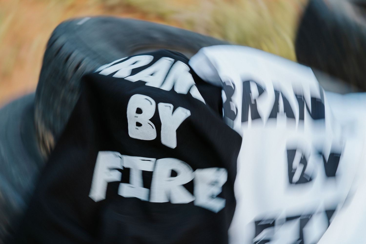 A motion-blurred shot of black and white text with 'BY FIRE' visible on a dark surface.