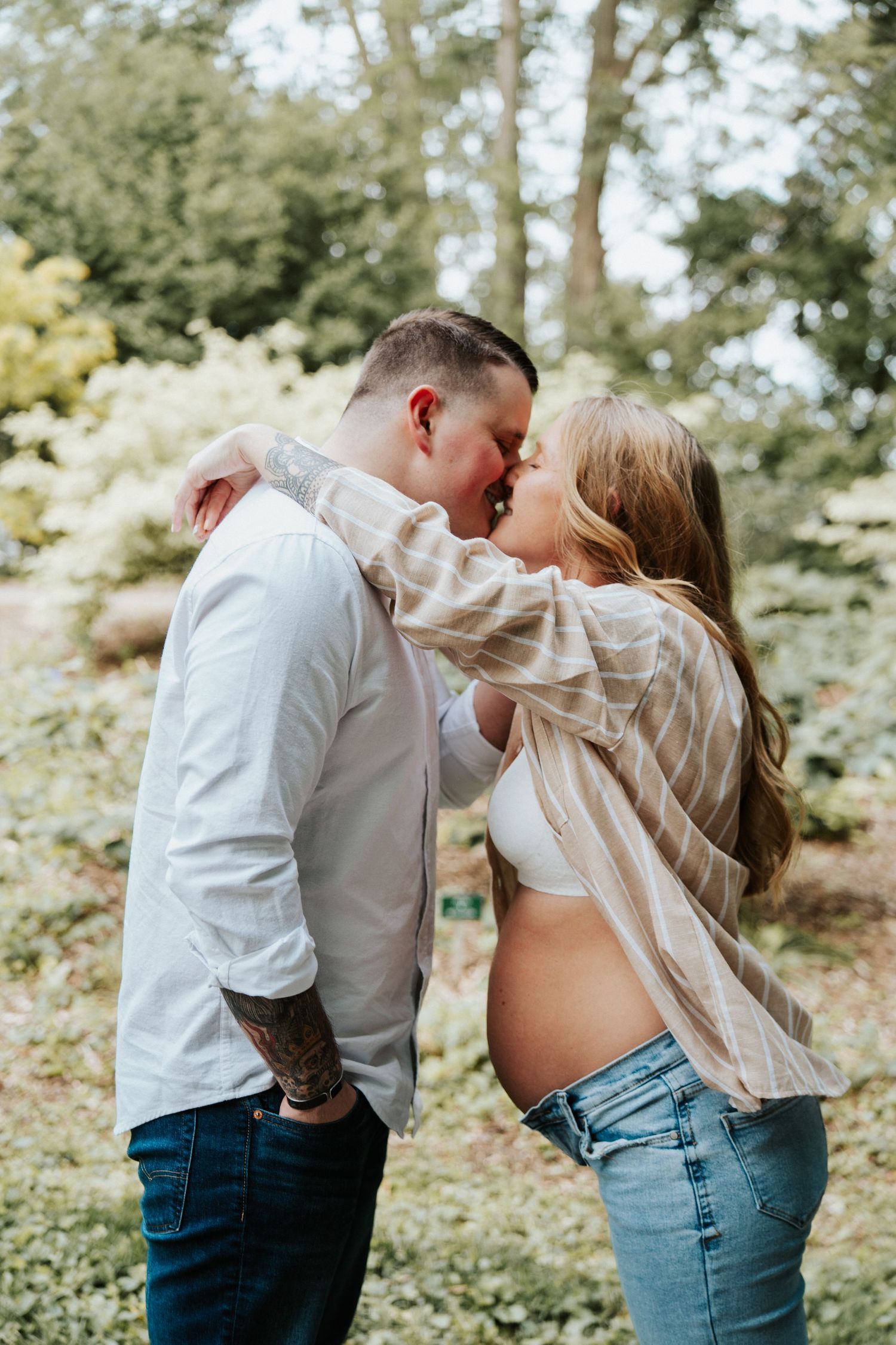A romantic outdoor photo series showing a couple kissing in a wooded setting among green foliage.