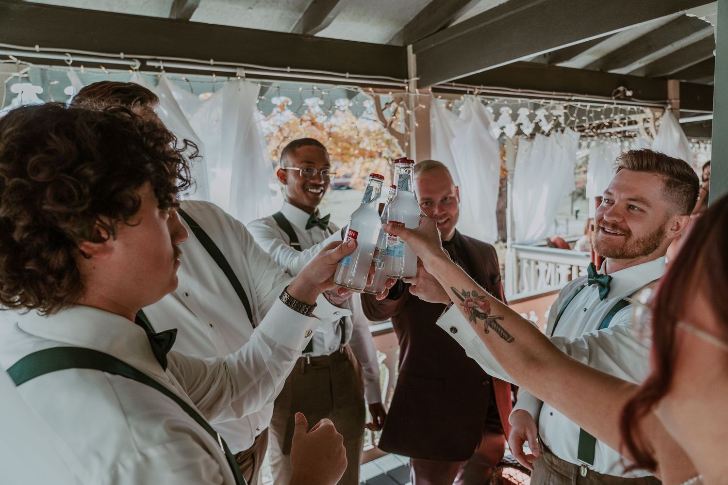 A group of people toasting with champagne glasses on a covered porch during a celebration.