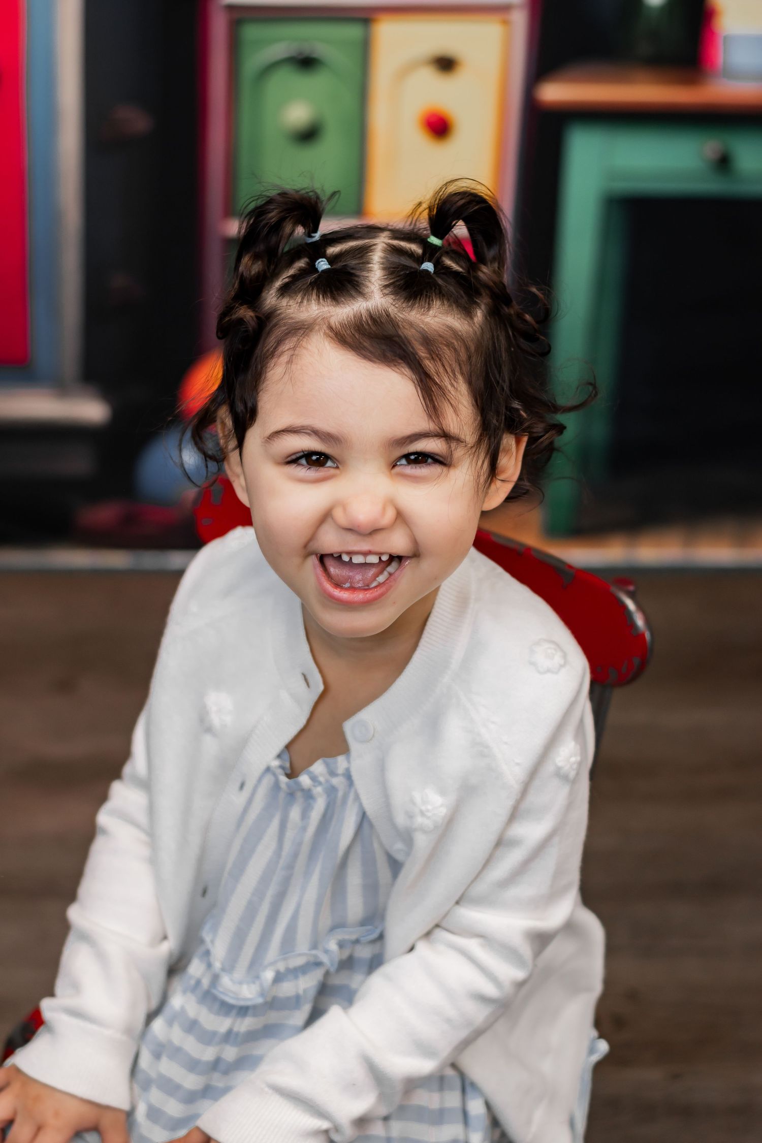 A child in a white cardigan and blue dress smiles brightly in a series of four connected photos.