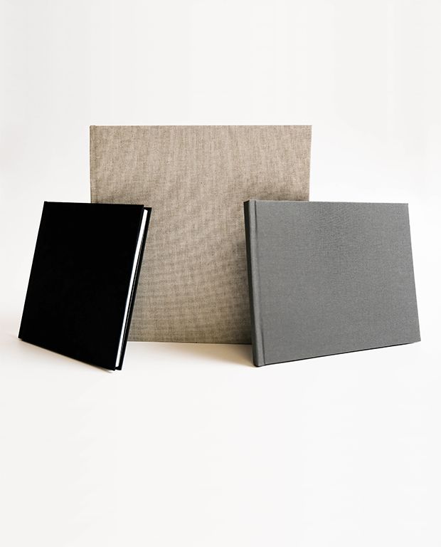 Linen layflat photo album covers in neutral tones displayed together.