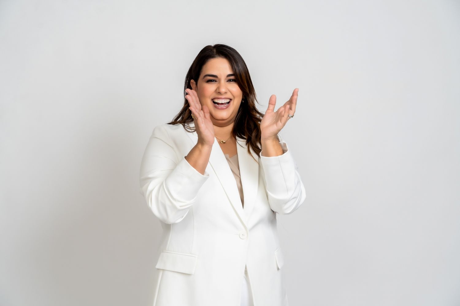 A joyful figure in a crisp white business suit laughs expressively against a light gray background.