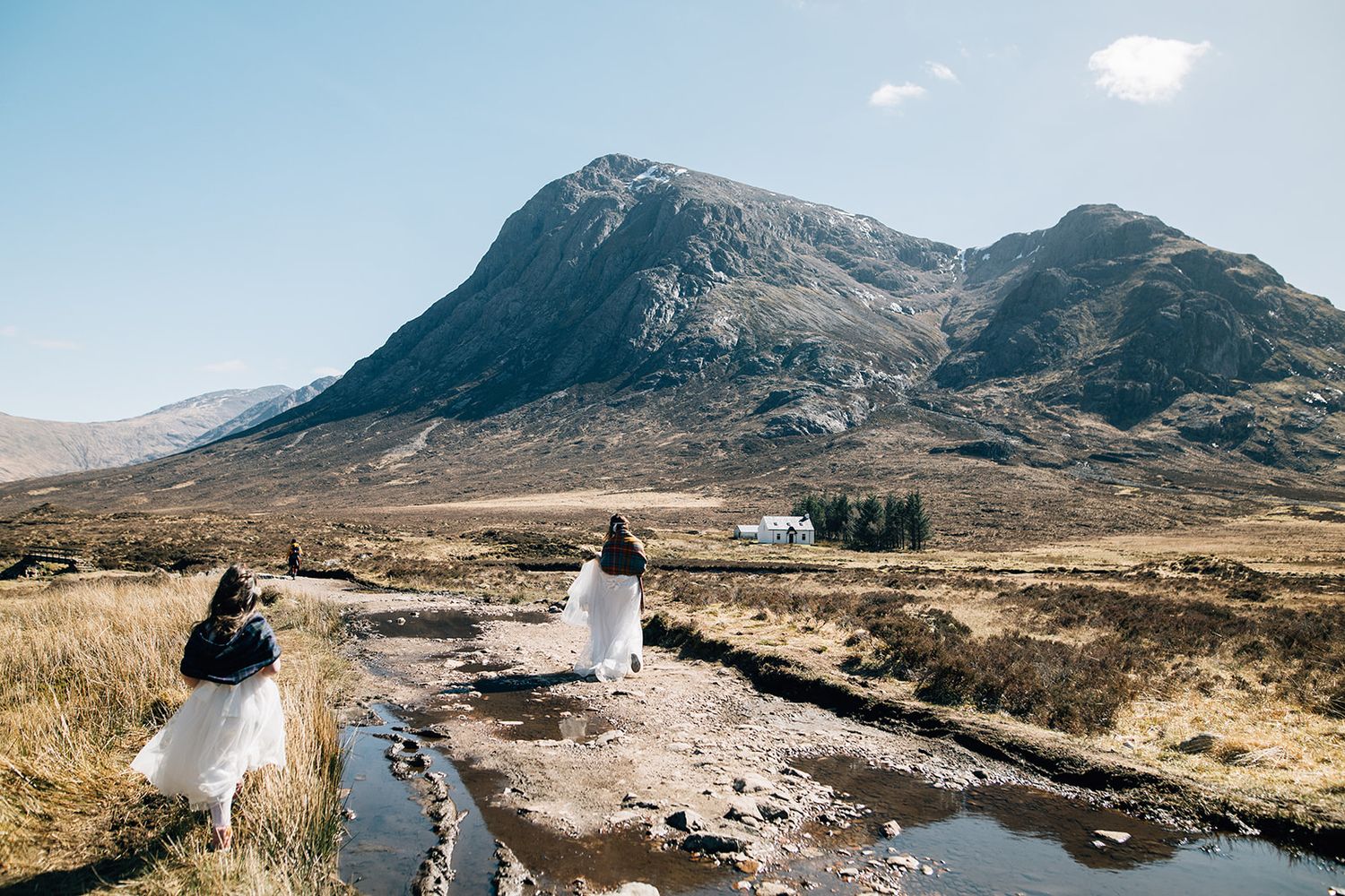 Dramatic mountain landscape in Scotland's Glencoe region with rugged peaks and moody skies in the distance.