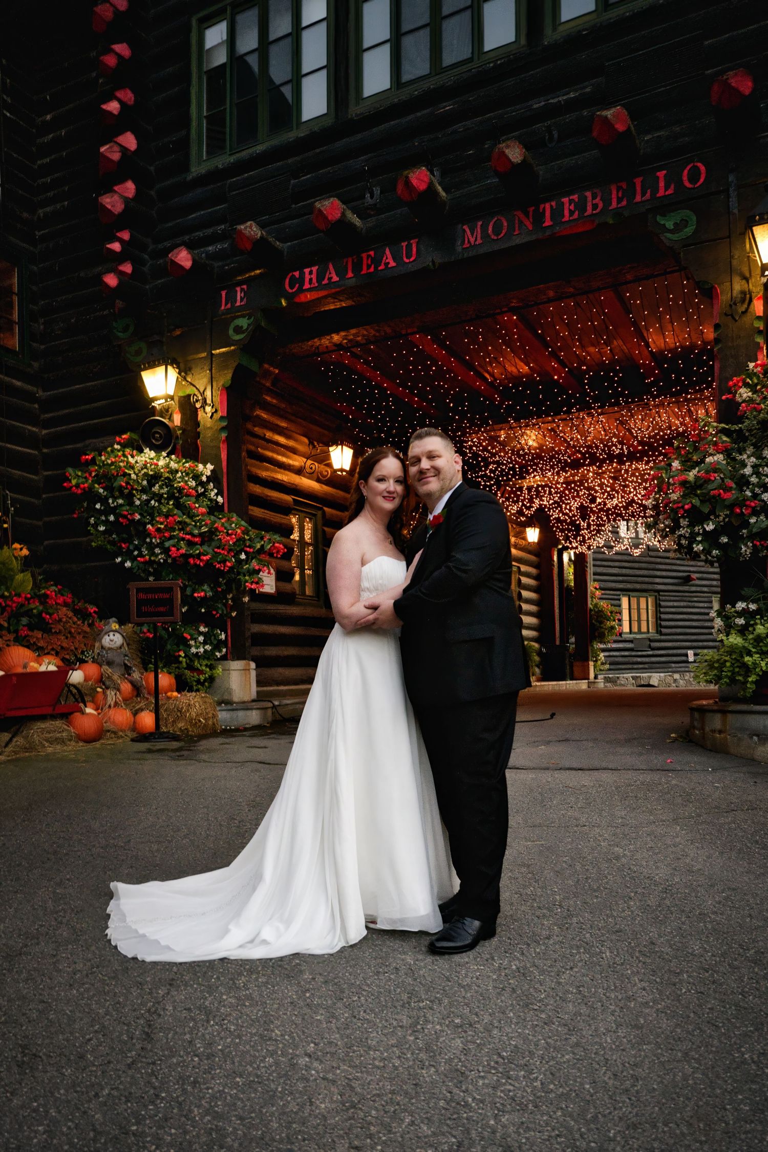 A couple poses outside Le Chateau Montebello with red lanterns and autumn decor creating a romantic ambiance.
