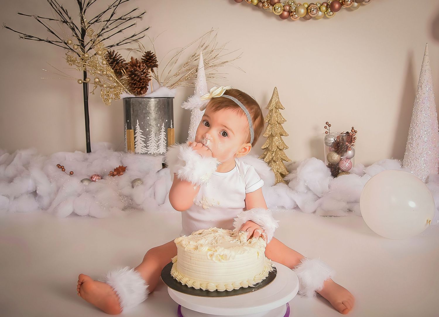 A series of photos showing a cake smash photo session with a white and gold birthday cake and decorations.