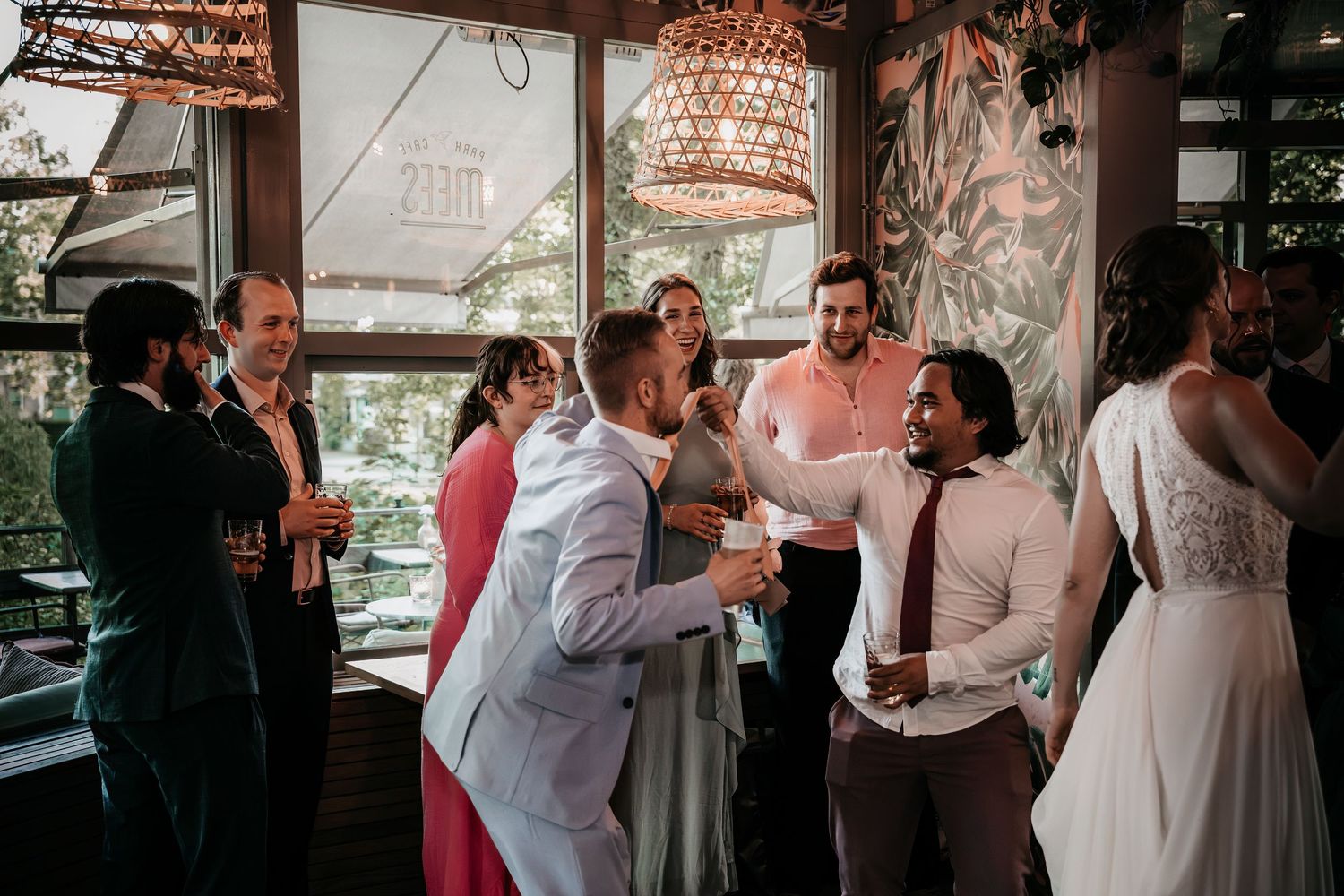Wedding guests laughing and socializing with drinks at a stylish indoor wedding reception venue.