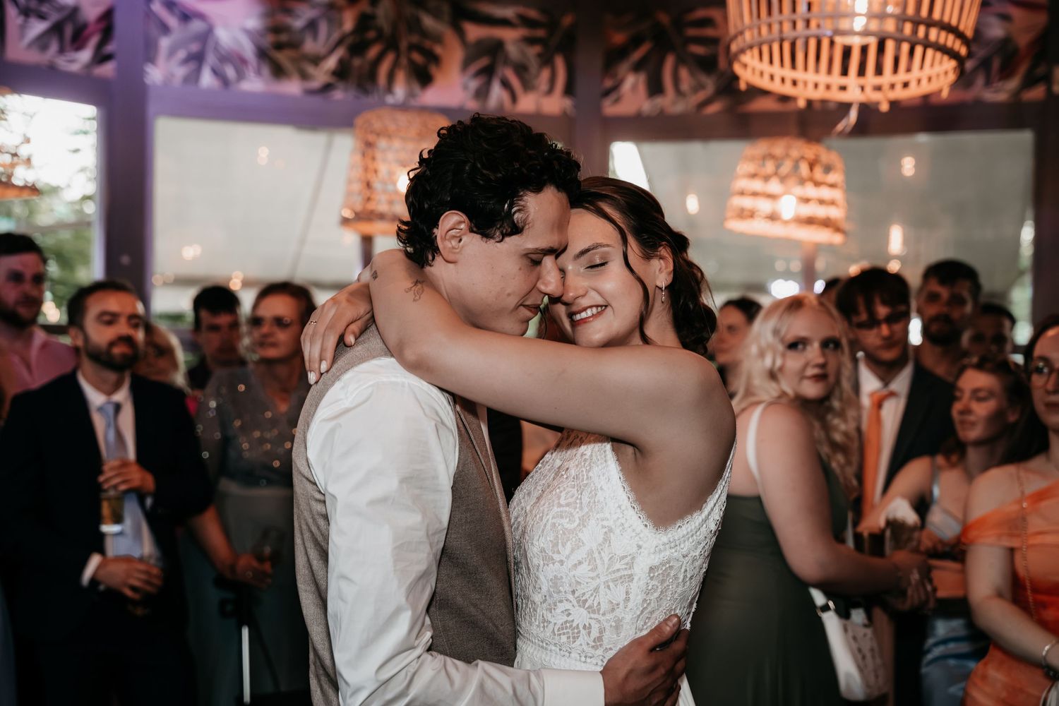 Newlyweds sharing an intimate slow dance moment with eyes closed at their wedding reception.