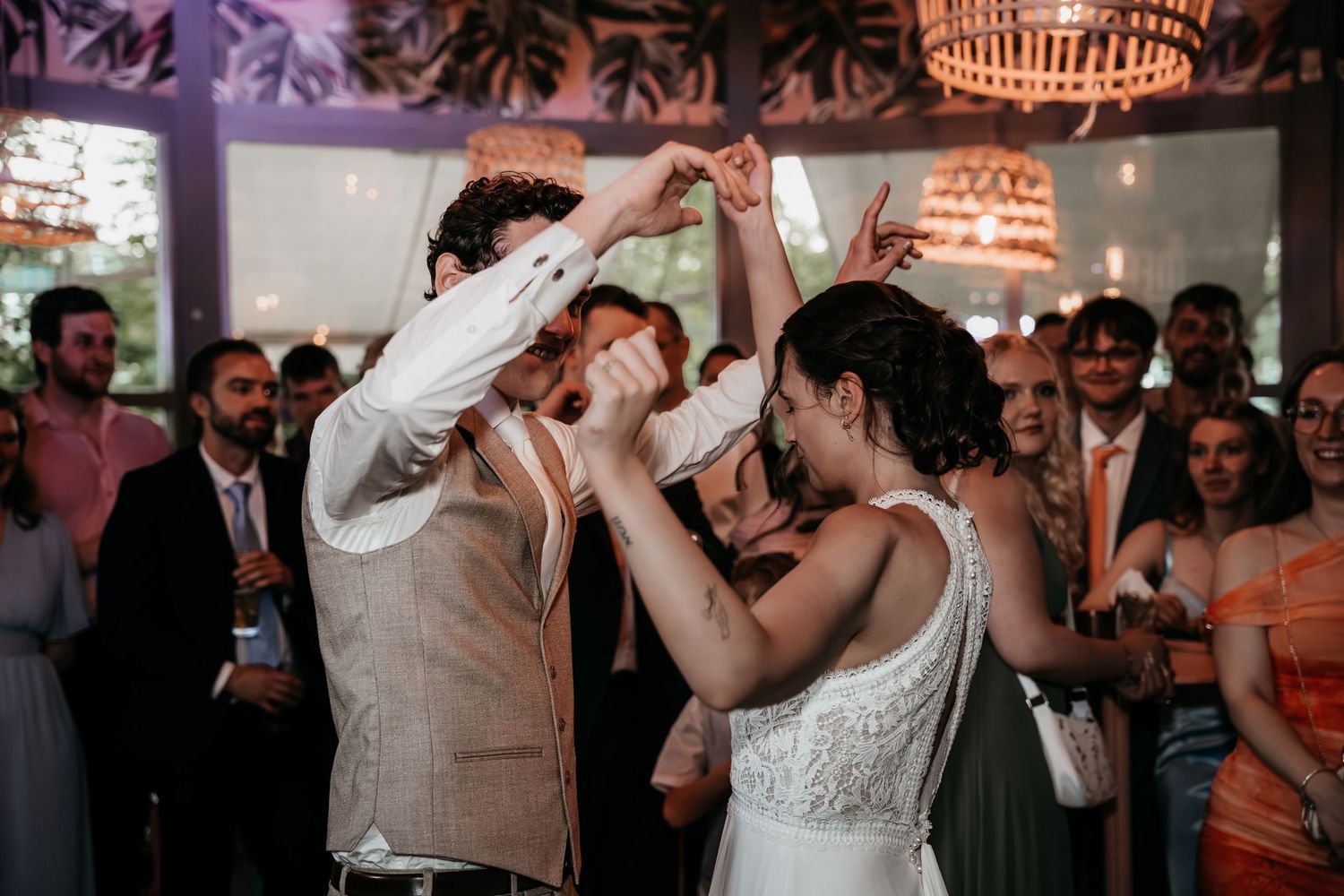 Bride and groom dancing energetically together holding hands at their wedding reception celebration.