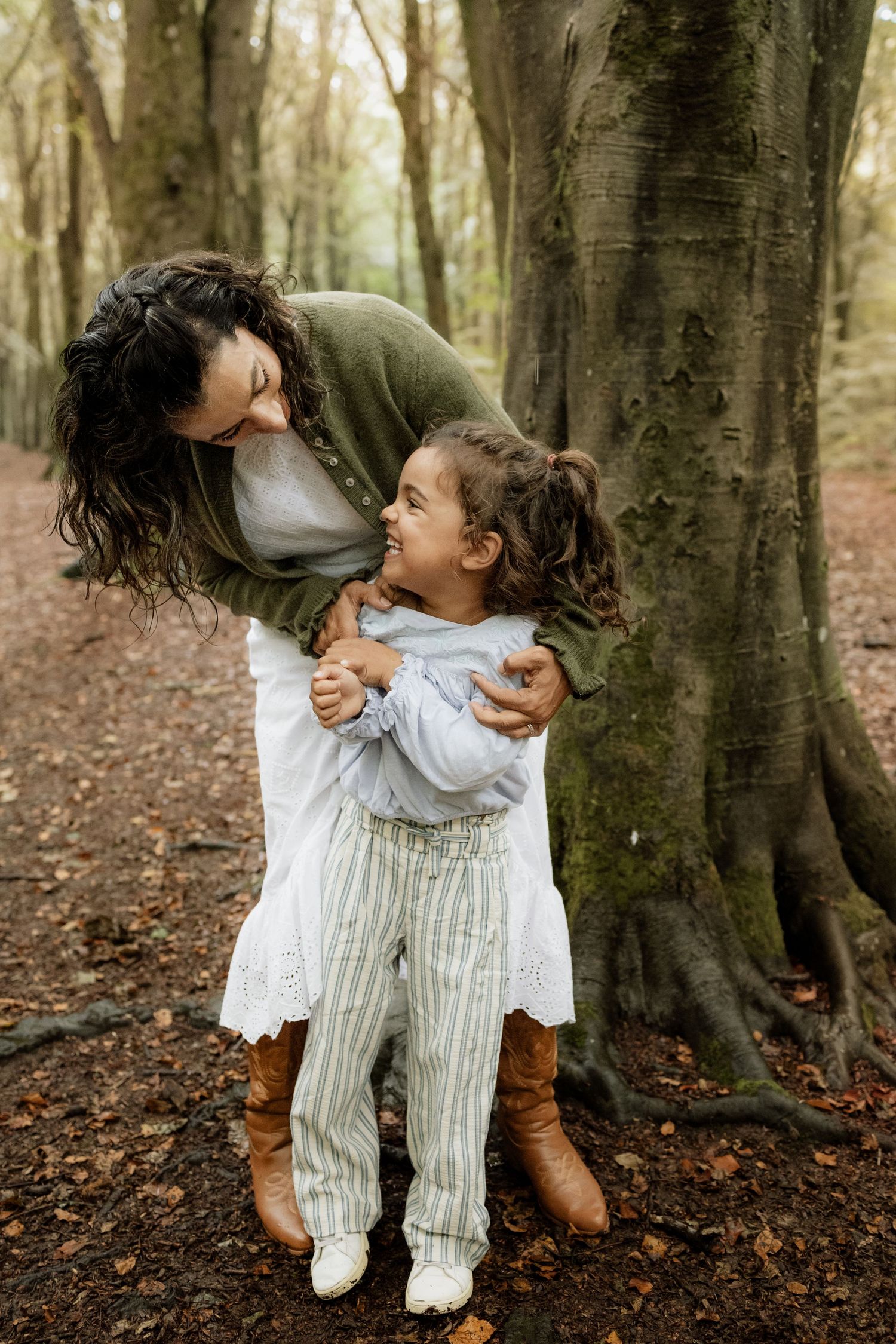 Mum laughing with her young daughter during a family photoshoot in Micheldever Woods