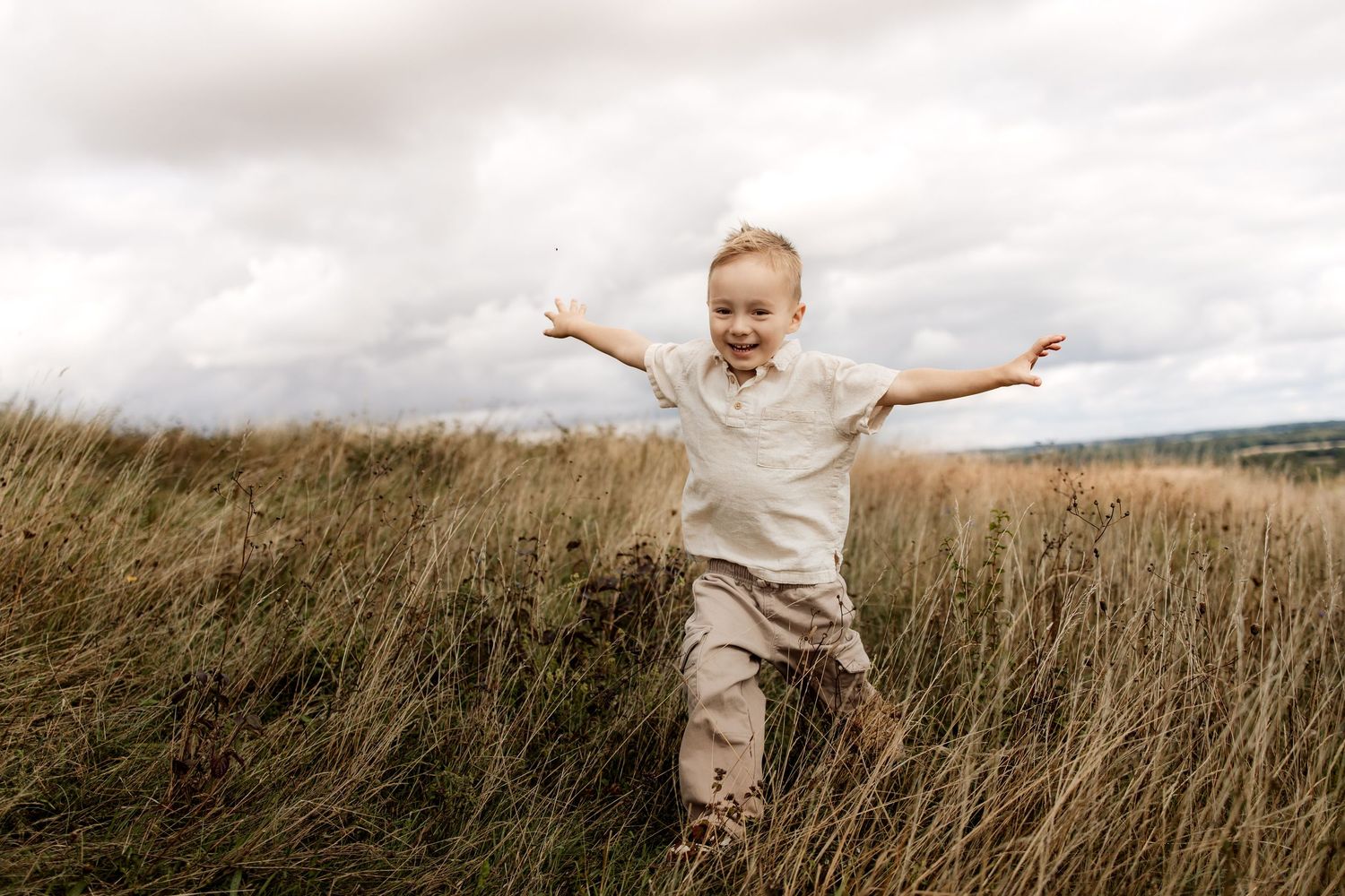 Boy running in long grass during a natural family photography session in Winchester