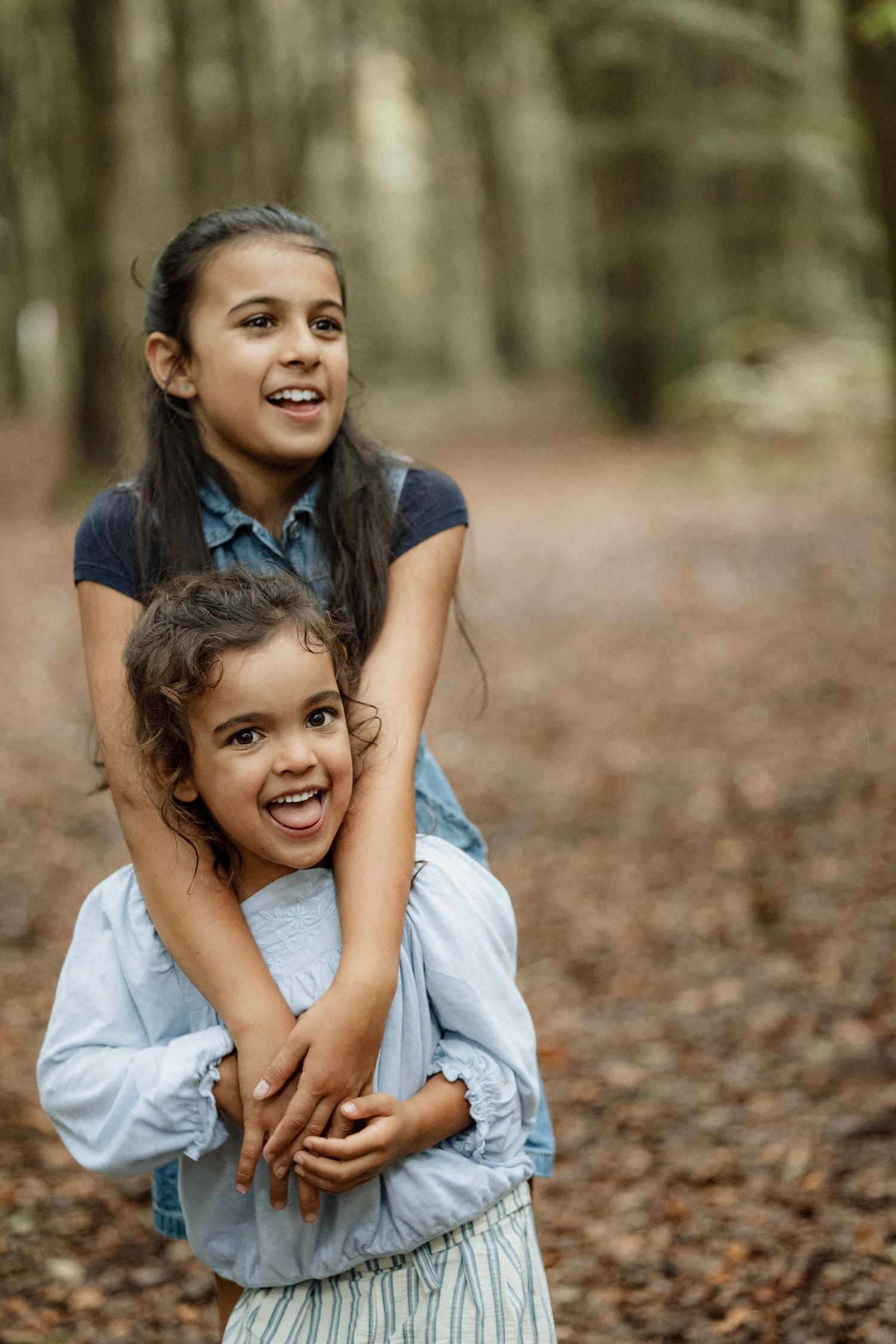 Two sisters laughing together during a child-led family photoshoot near Winchester