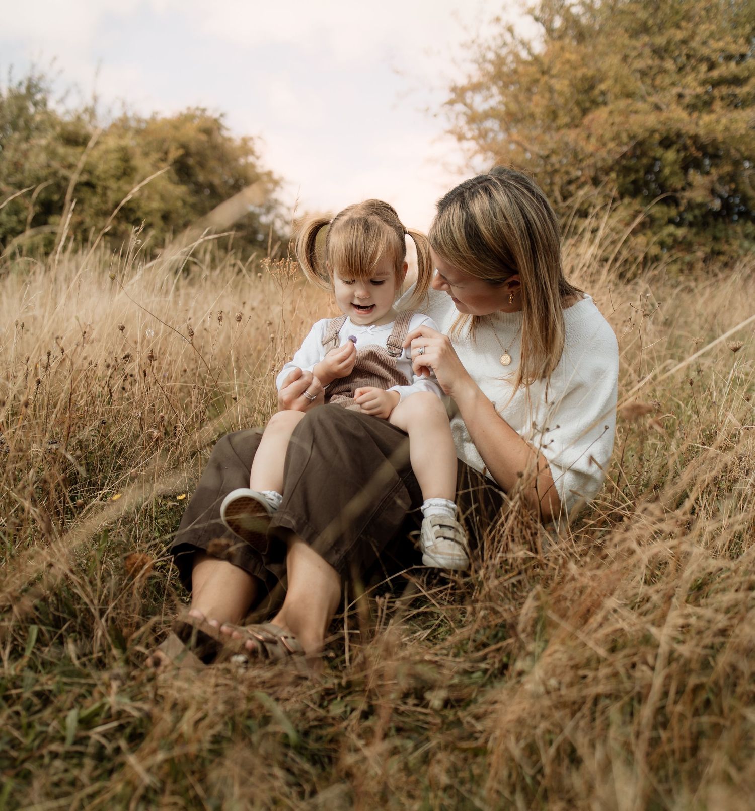 Mum and Daughter sit in a field in Winchester during an outdoor photoshoot