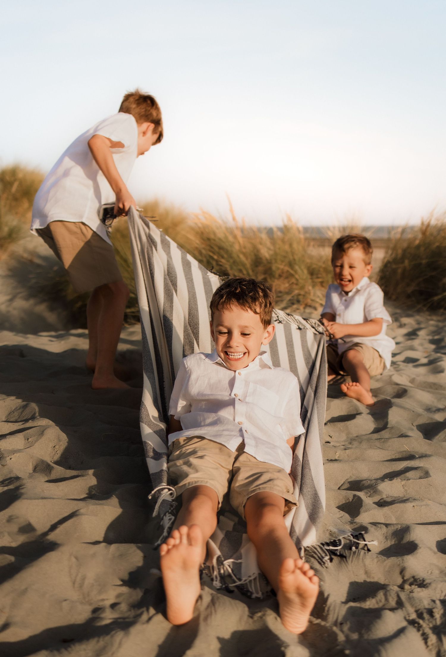 Three brothers playing together on the beach during a relaxed family photography session, The school aged boys live in Southampton