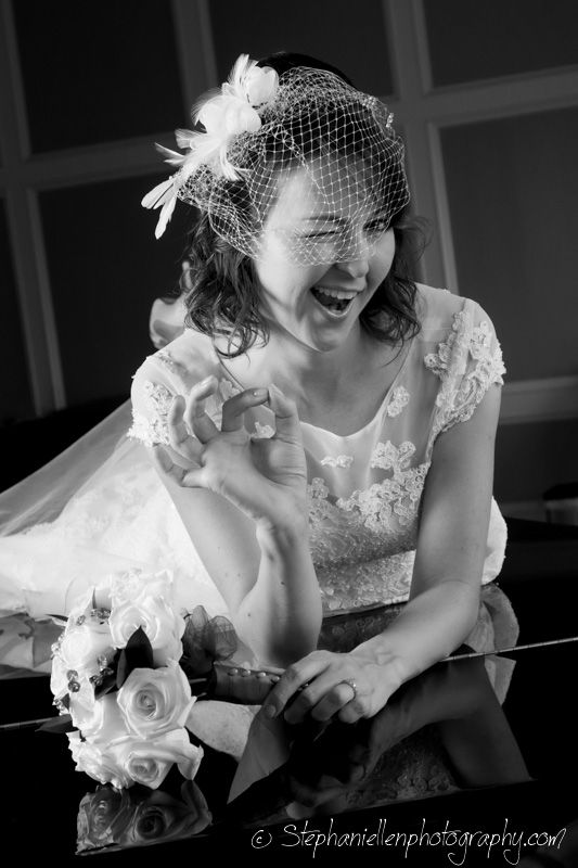 Black and white portrait of laughing bride in lace dress and birdcage veil with bouquet.