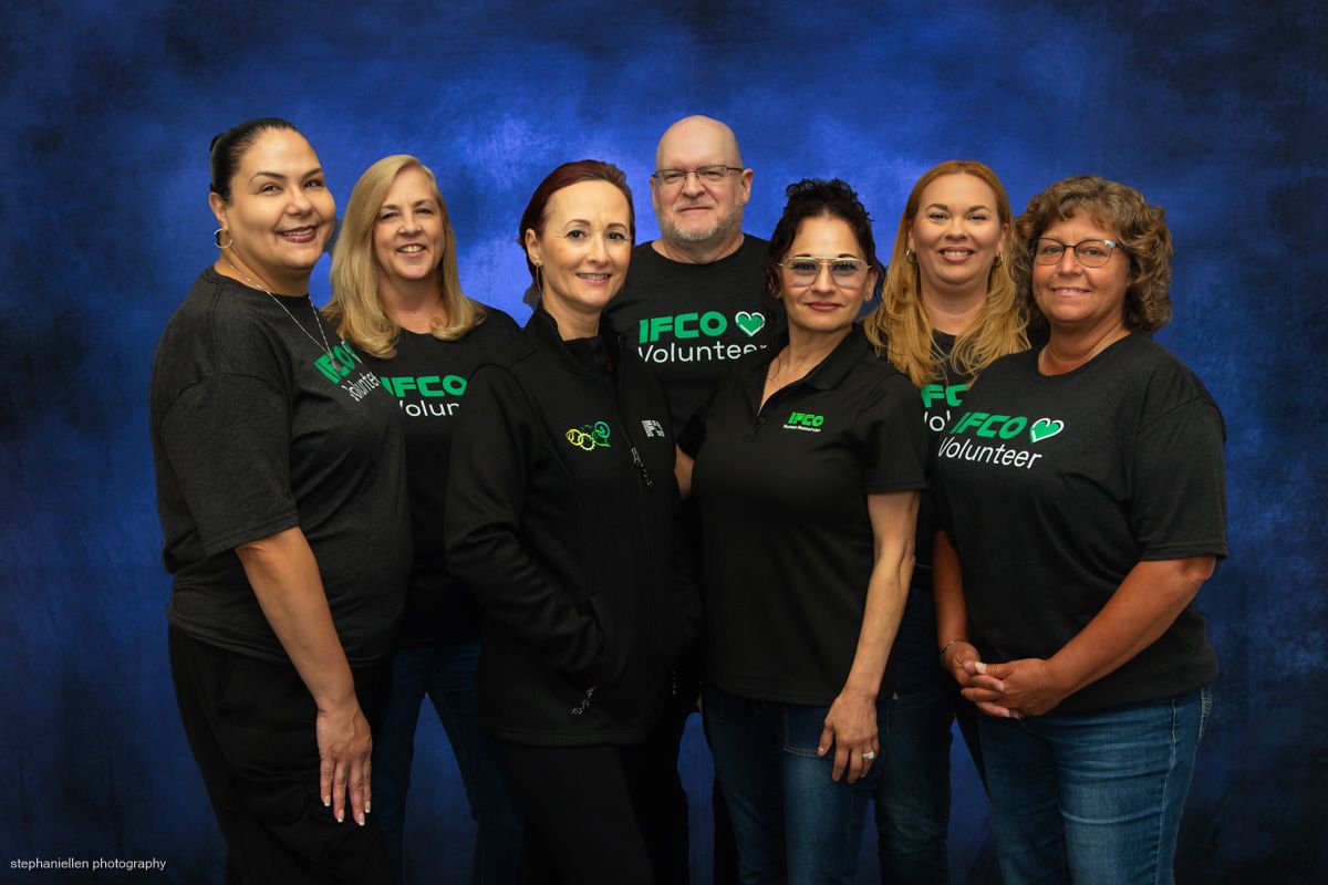 Seven IFCO volunteers in matching black shirts pose together for a group photo.