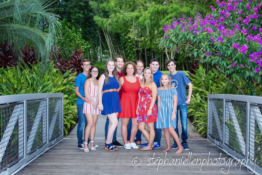 Large family group posing together on a wooden bridge surrounded by lush tropical greenery.
