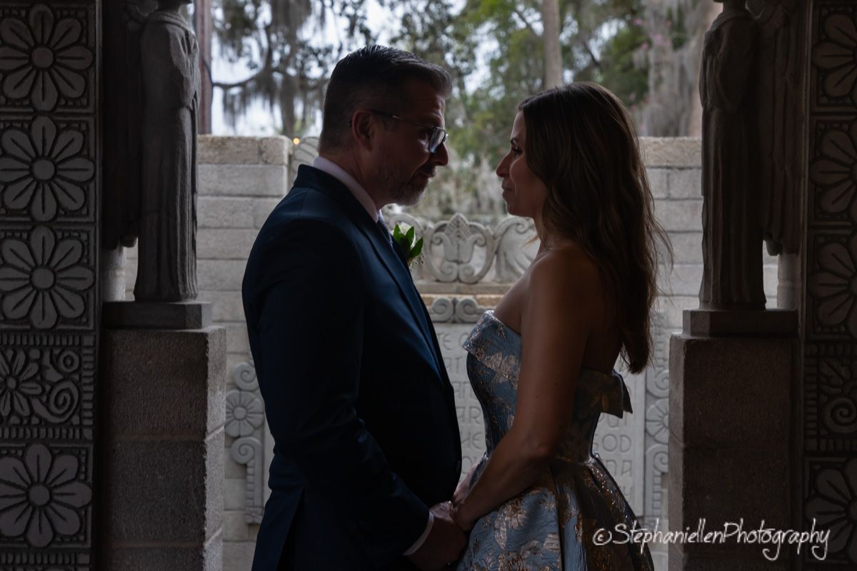 Bride and groom share intimate moment framed by decorative stone archway at wedding.