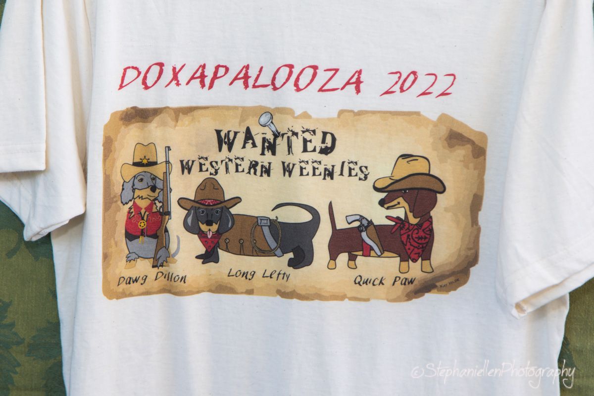 Doxapalooza 2022 white t-shirt featuring cartoon dachshunds dressed as western cowboys wanted poster.