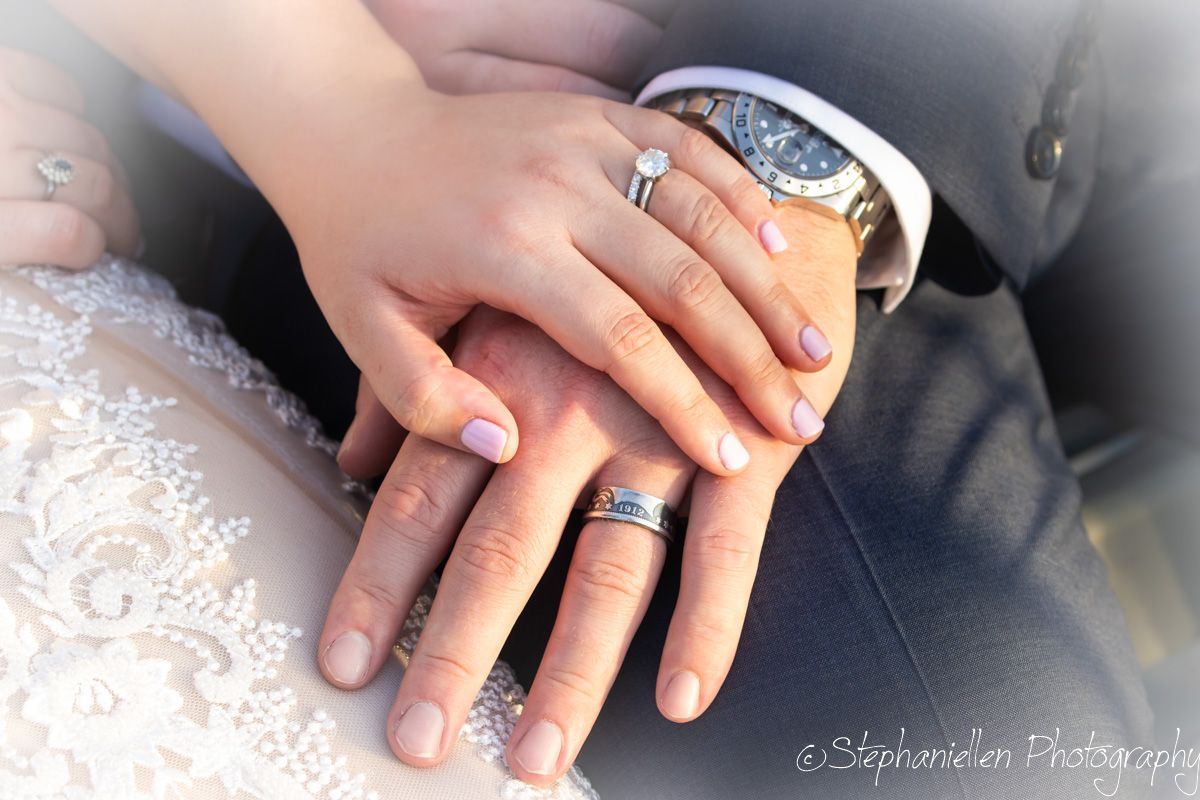 Close-up of wedding couple hands showing diamond engagement ring and matching wedding bands.