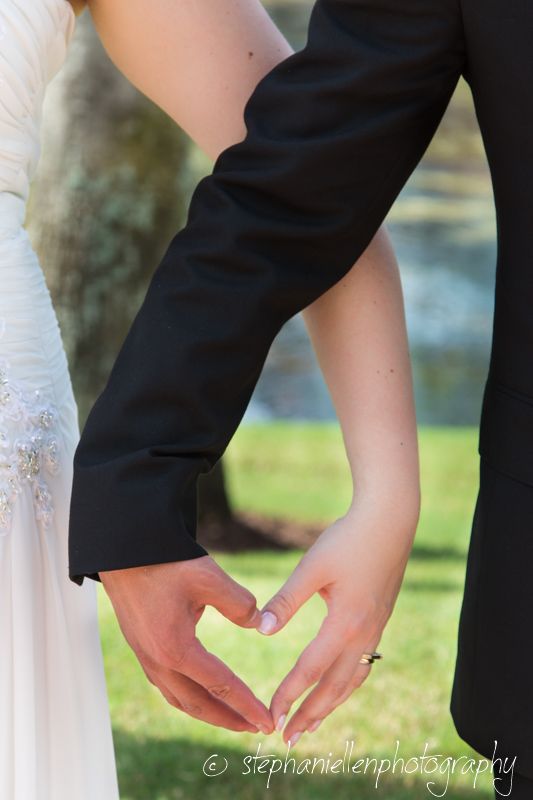 Bride and groom forming a heart shape with their hands, showcasing wedding rings, captured by Stephanie Ellen Photography.
