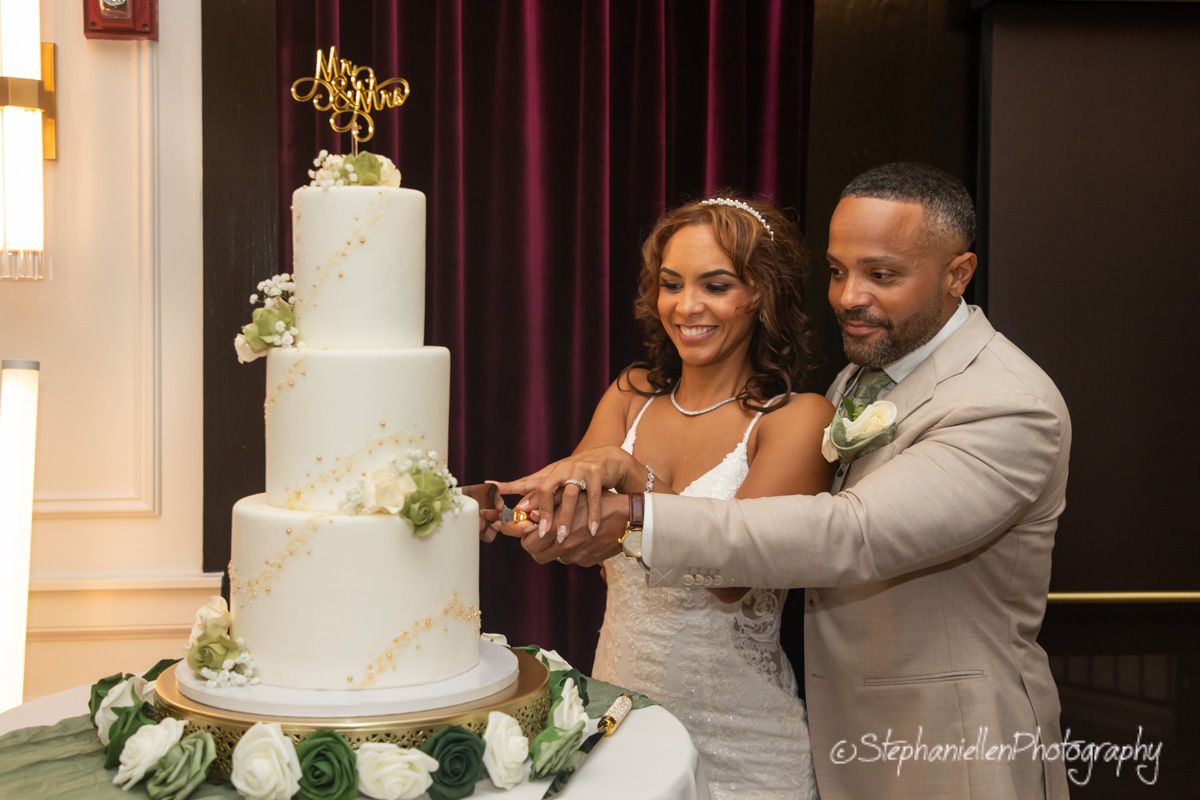 Bride and groom cutting their elegant four-tier white wedding cake together.