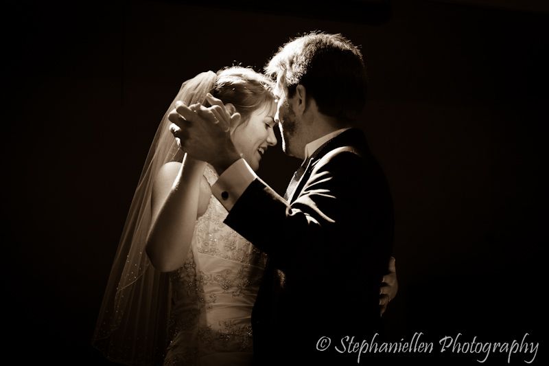 Romantic sepia-toned wedding photo of bride and groom sharing first dance.