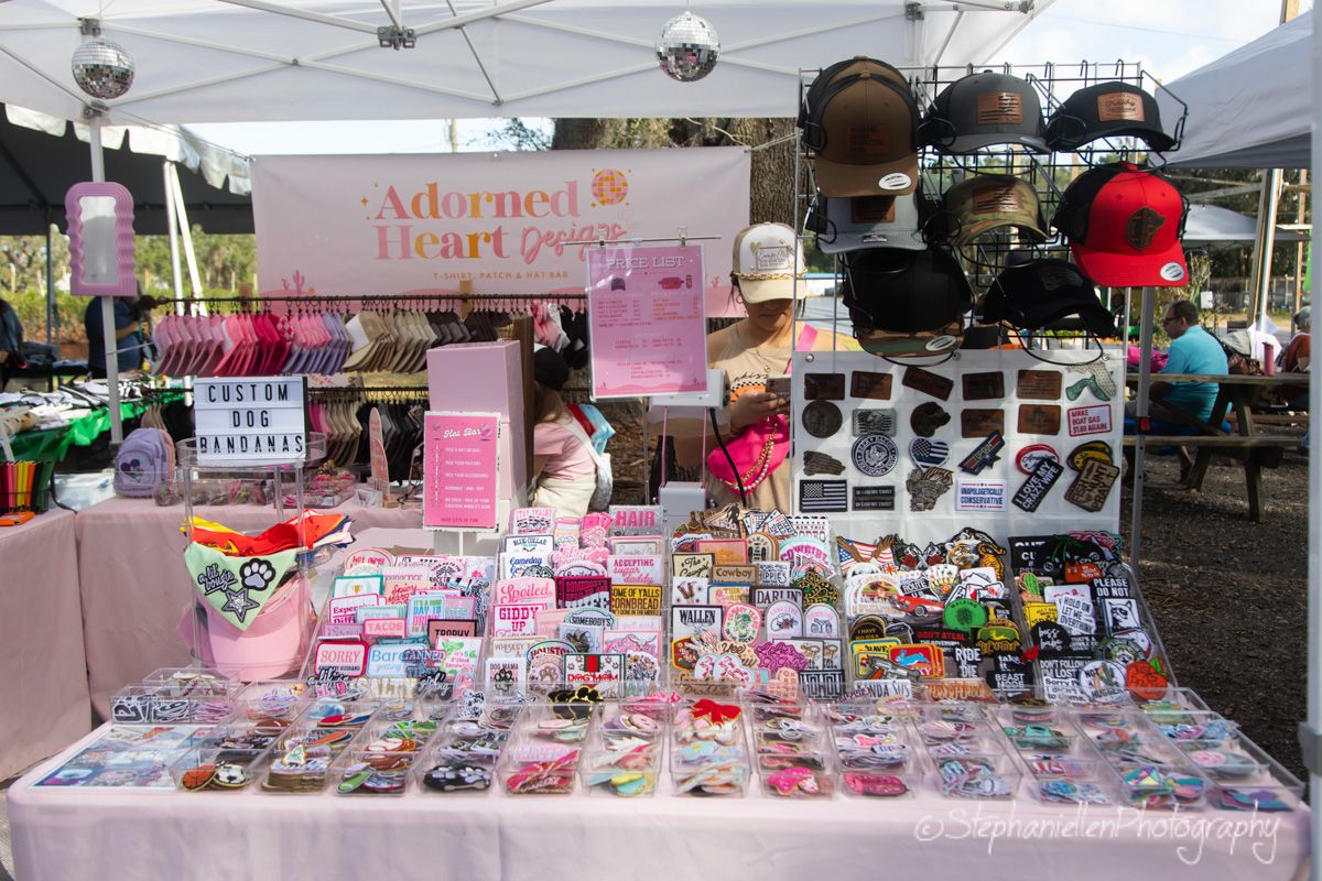 Adorned Heart Goods vendor booth displaying custom dog bandanas and accessories at an outdoor market.