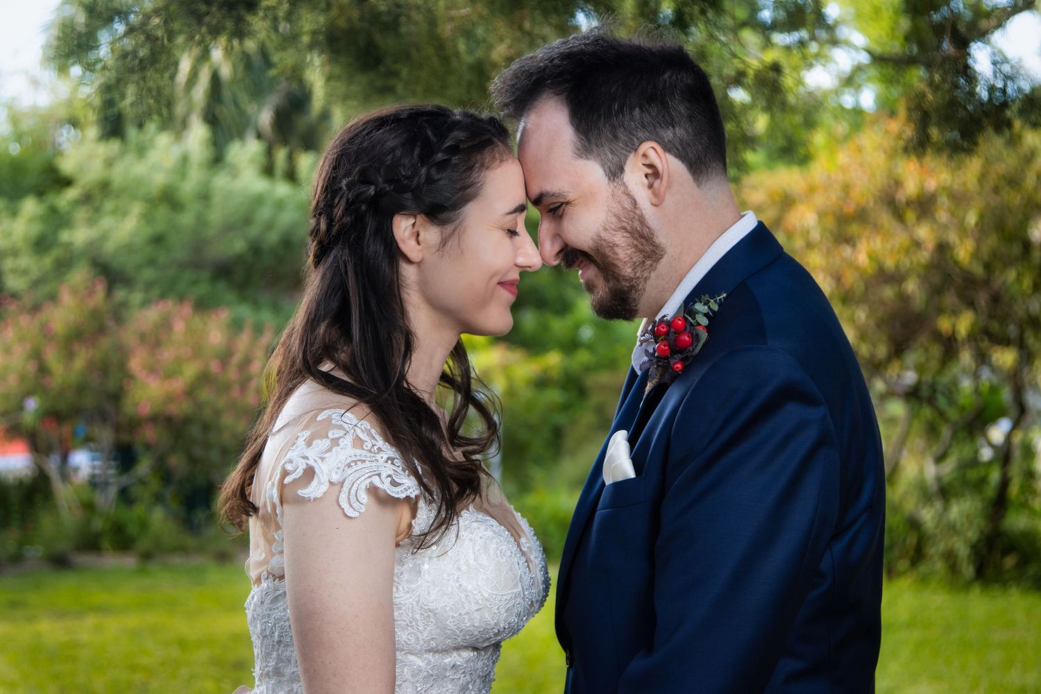 Bride and groom share an intimate forehead touch moment in a sunlit garden on their wedding day.