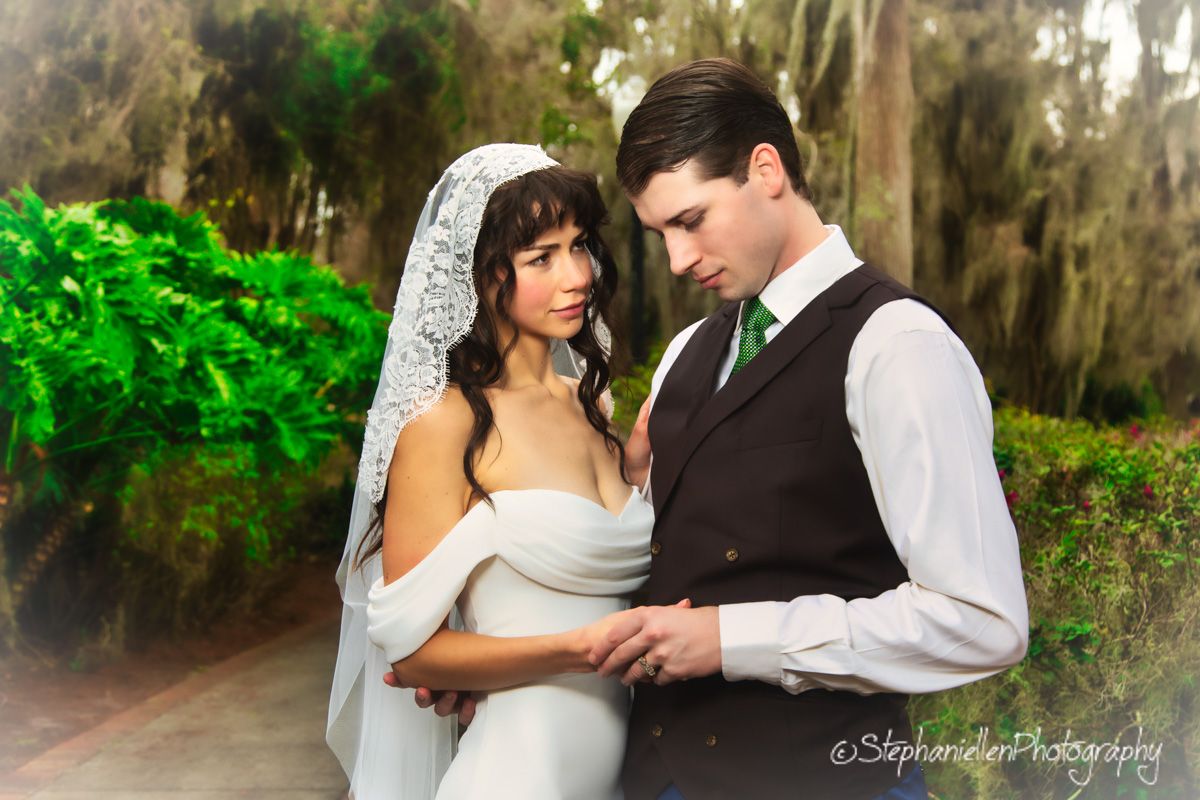Bride and groom share intimate moment in dreamy moss-draped garden setting.