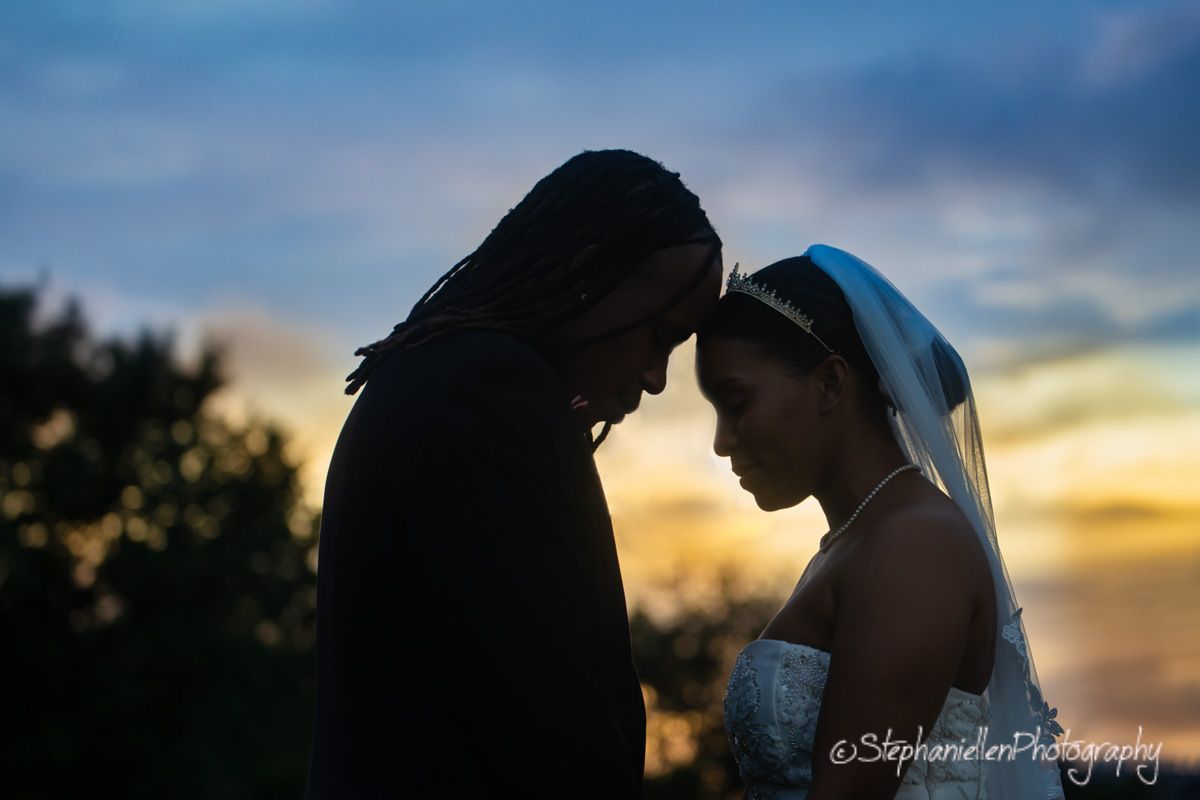 Silhouette of bride and groom touching foreheads at sunset wedding.