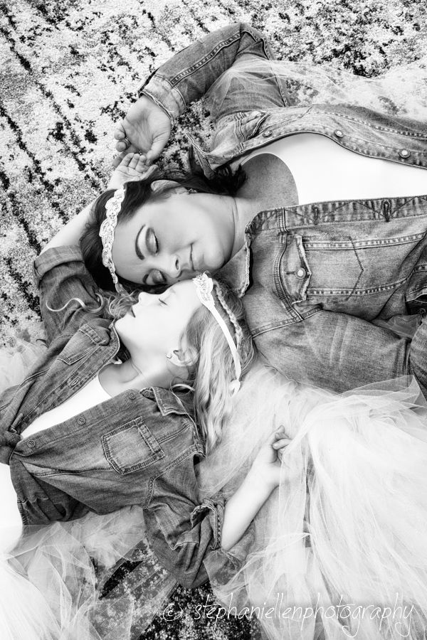 Black and white photo of bride and child lying down in denim jackets and tulle skirts.