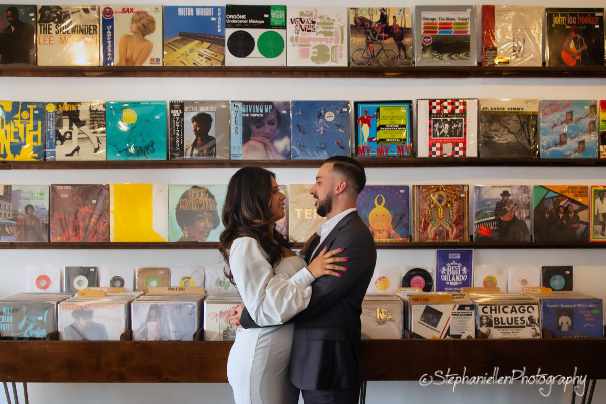 Couple sharing romantic moment facing each other in front of colorful vinyl record collection.