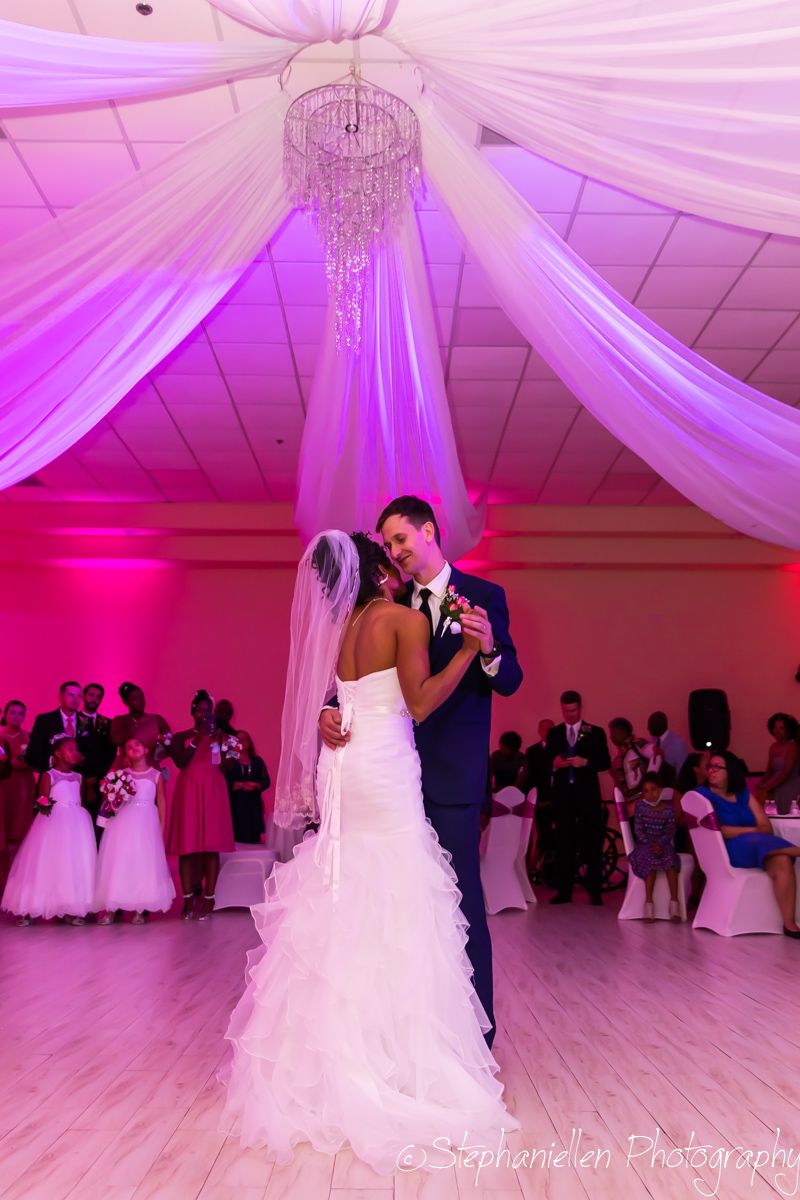 Bride and groom sharing their first dance under a chandelier with purple uplighting at their wedding reception.