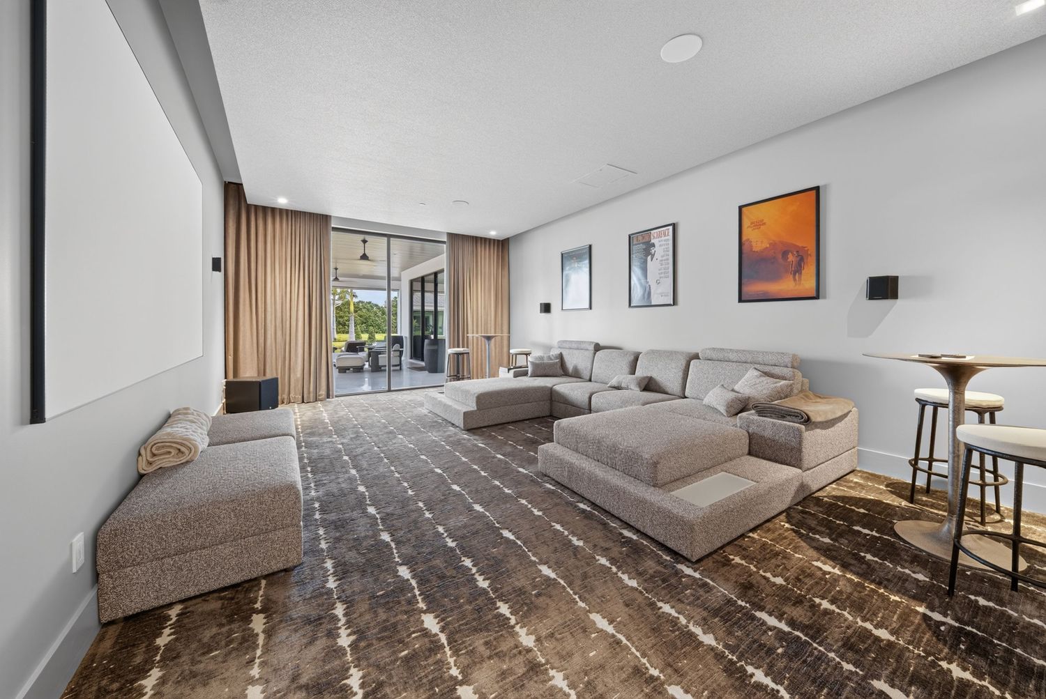 Spacious living room with large gray sectional, patterned rug, and sliding glass doors.