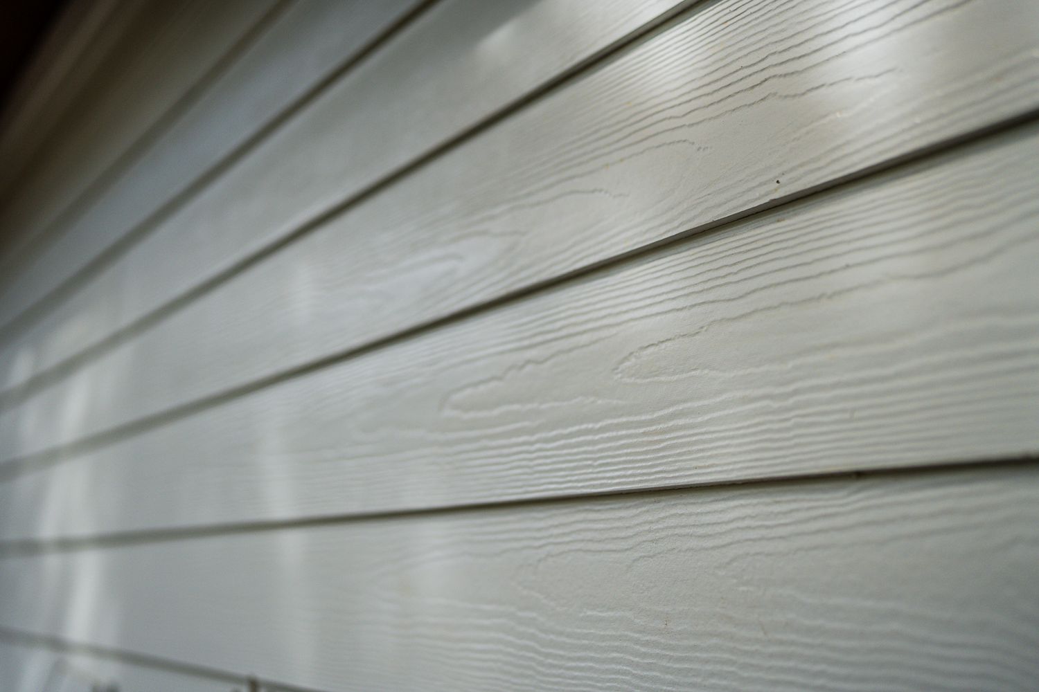 Close-up detail of white James Hardie fiber cement lap siding with wood grain texture.