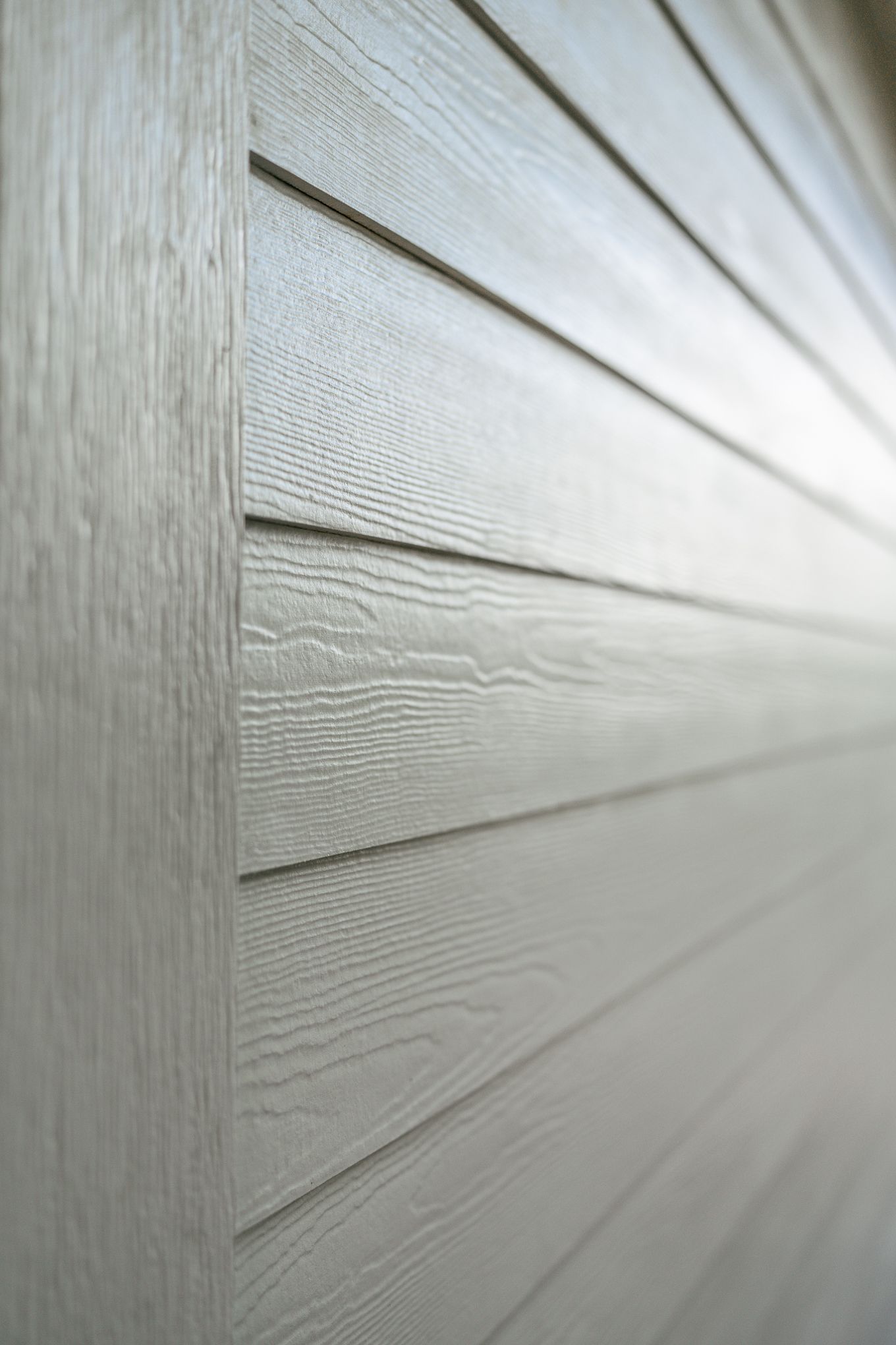 Close-up detail of white James Hardie fiber cement lap siding with wood grain texture pattern.