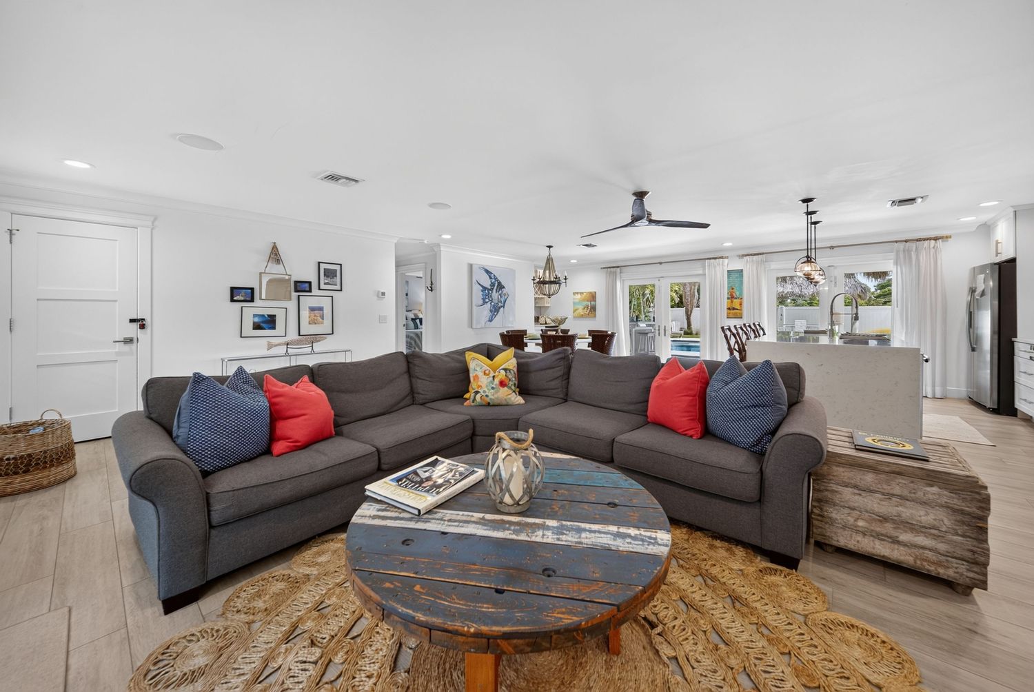 Spacious living room with gray sectional sofa, colorful accent pillows, rustic wood coffee table, and ceiling fan.