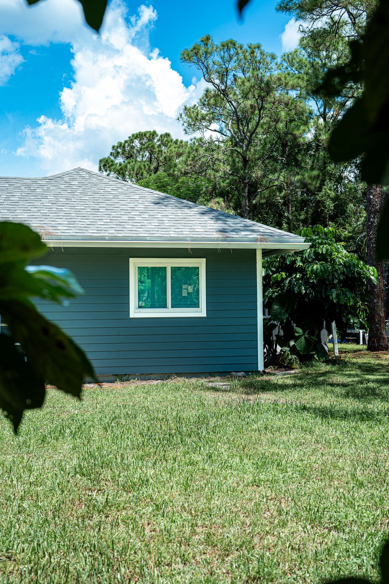 Completed home exterior with dark teal James Hardie fiber cement siding, white trim, and lush green yard.
