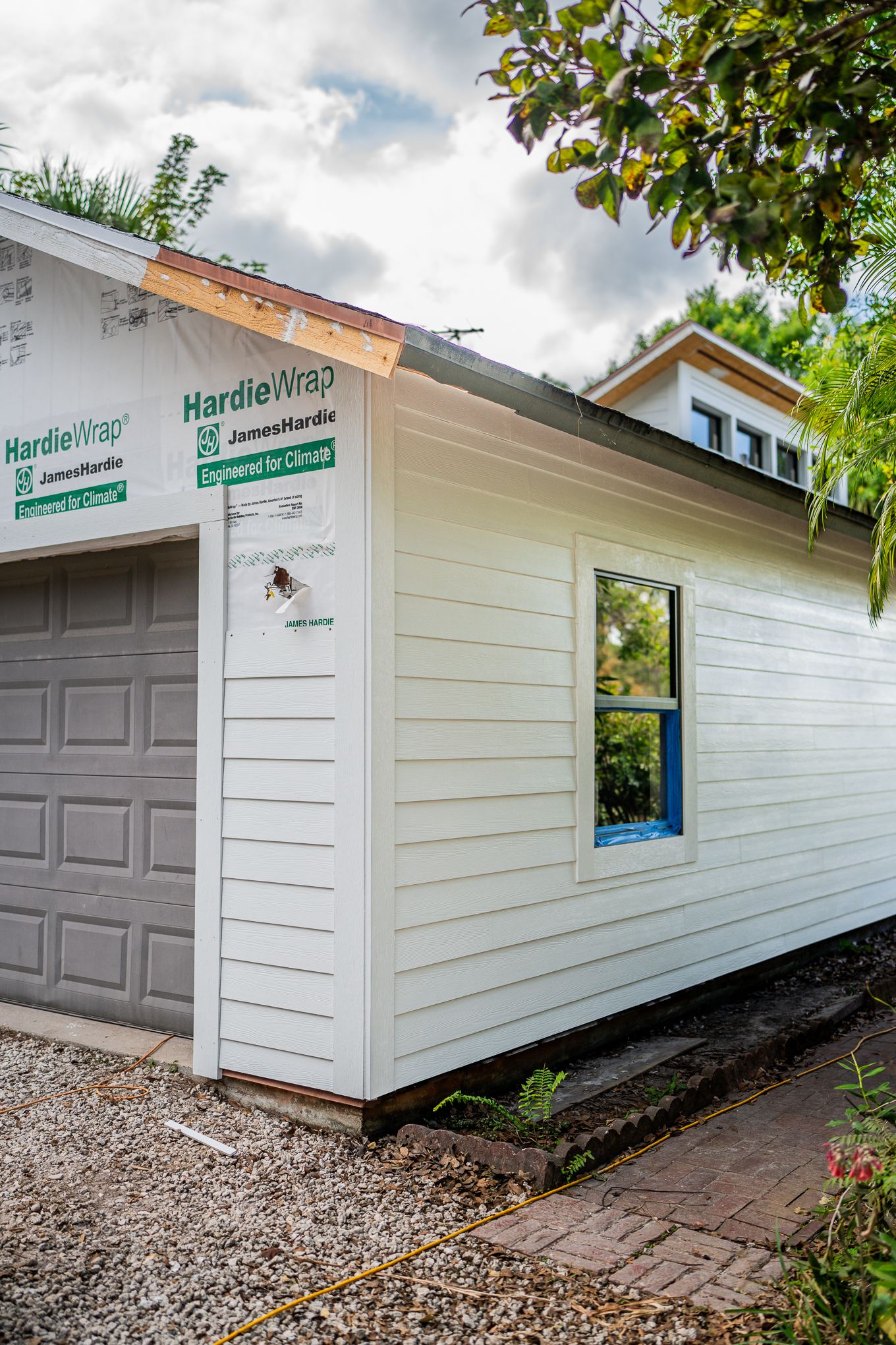 James Hardie HardieWrap fiber cement siding installation on white residential home exterior with garage.