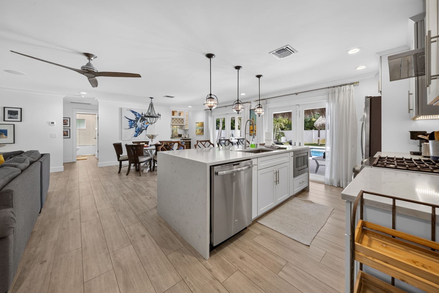 Modern open-concept kitchen with large island, stainless steel appliances, pendant lights, and hardwood floors.