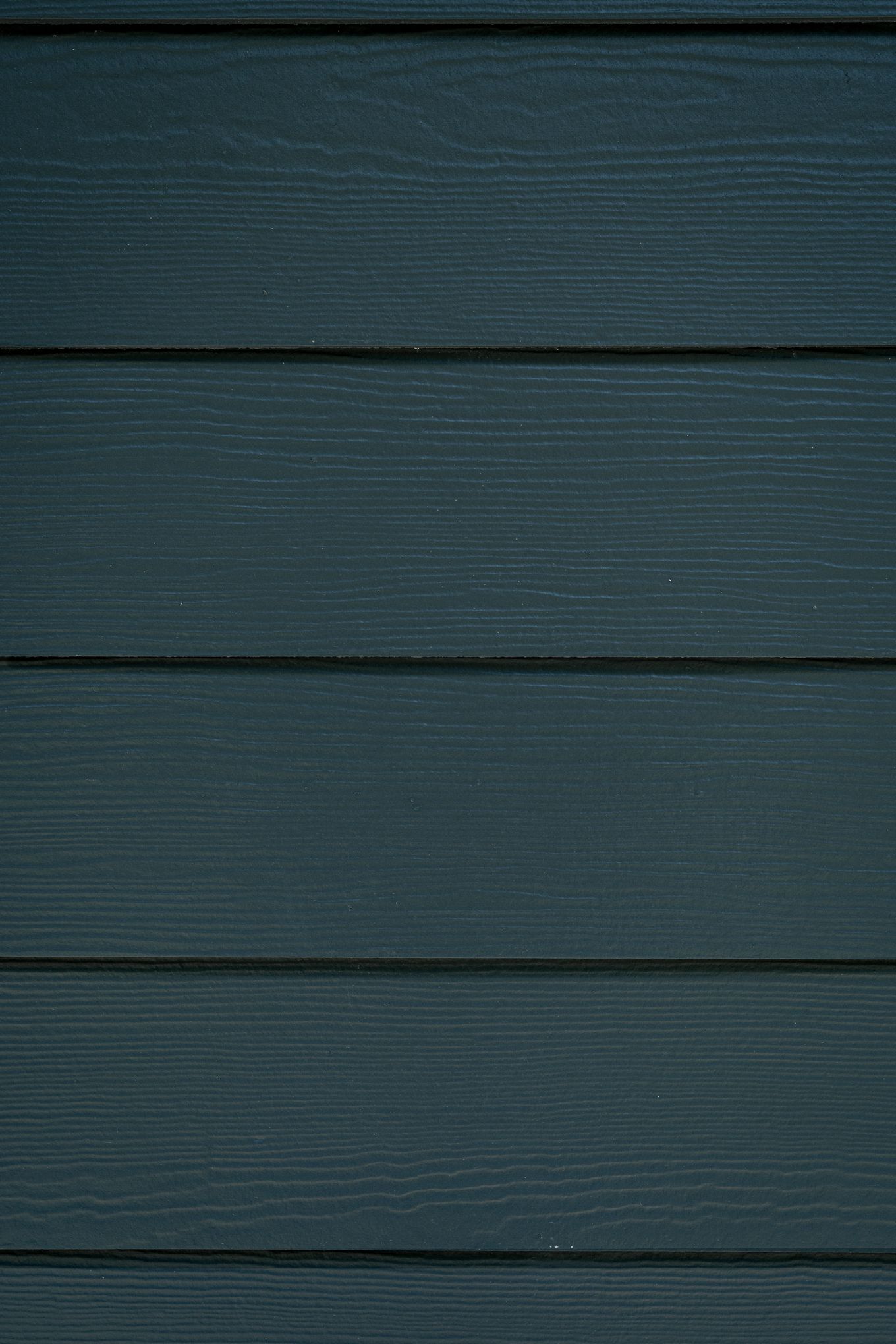 Close-up of dark teal horizontal lap siding with wood grain texture on exterior wall.