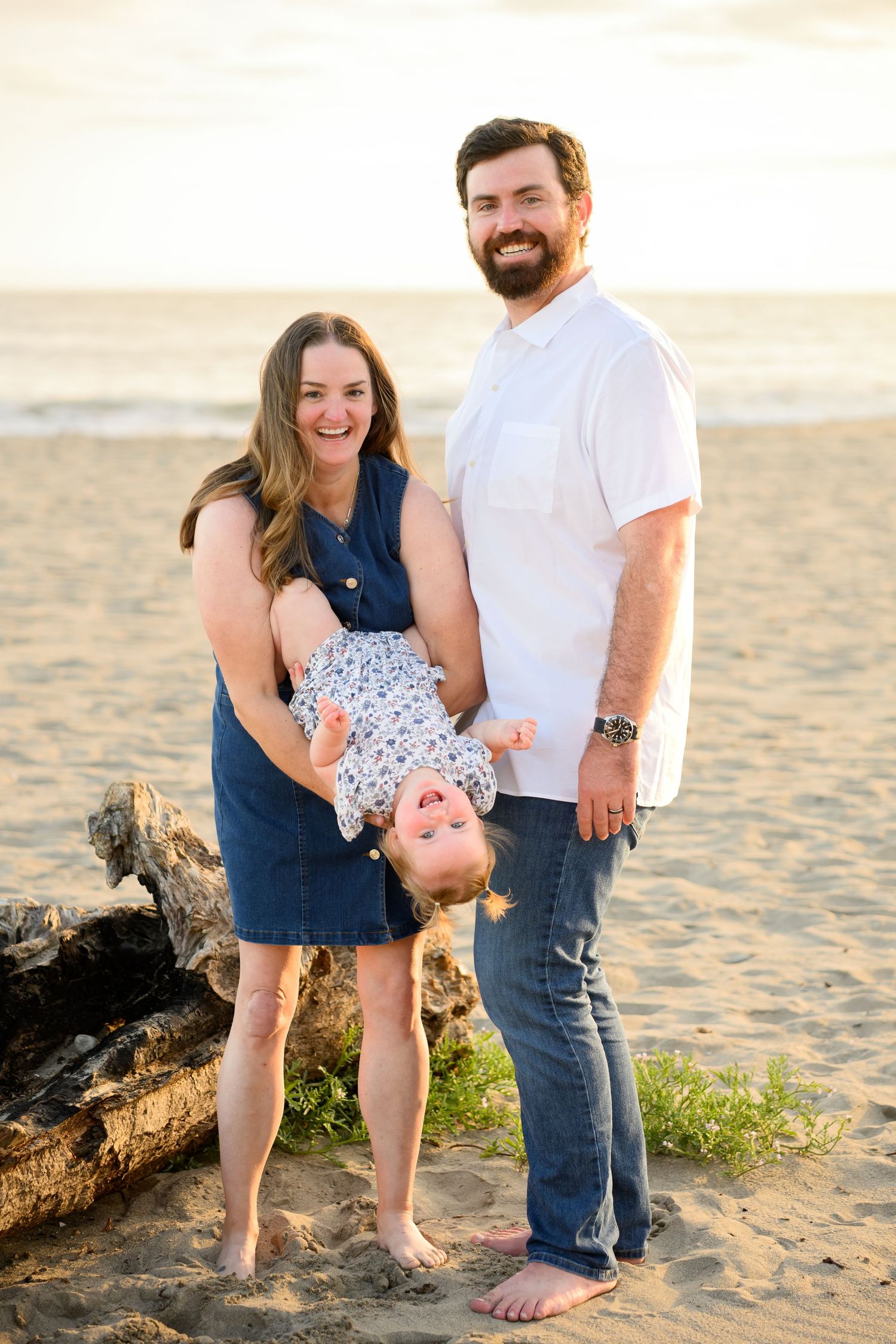 Picture of family at beach with daughter upside down and happy parents