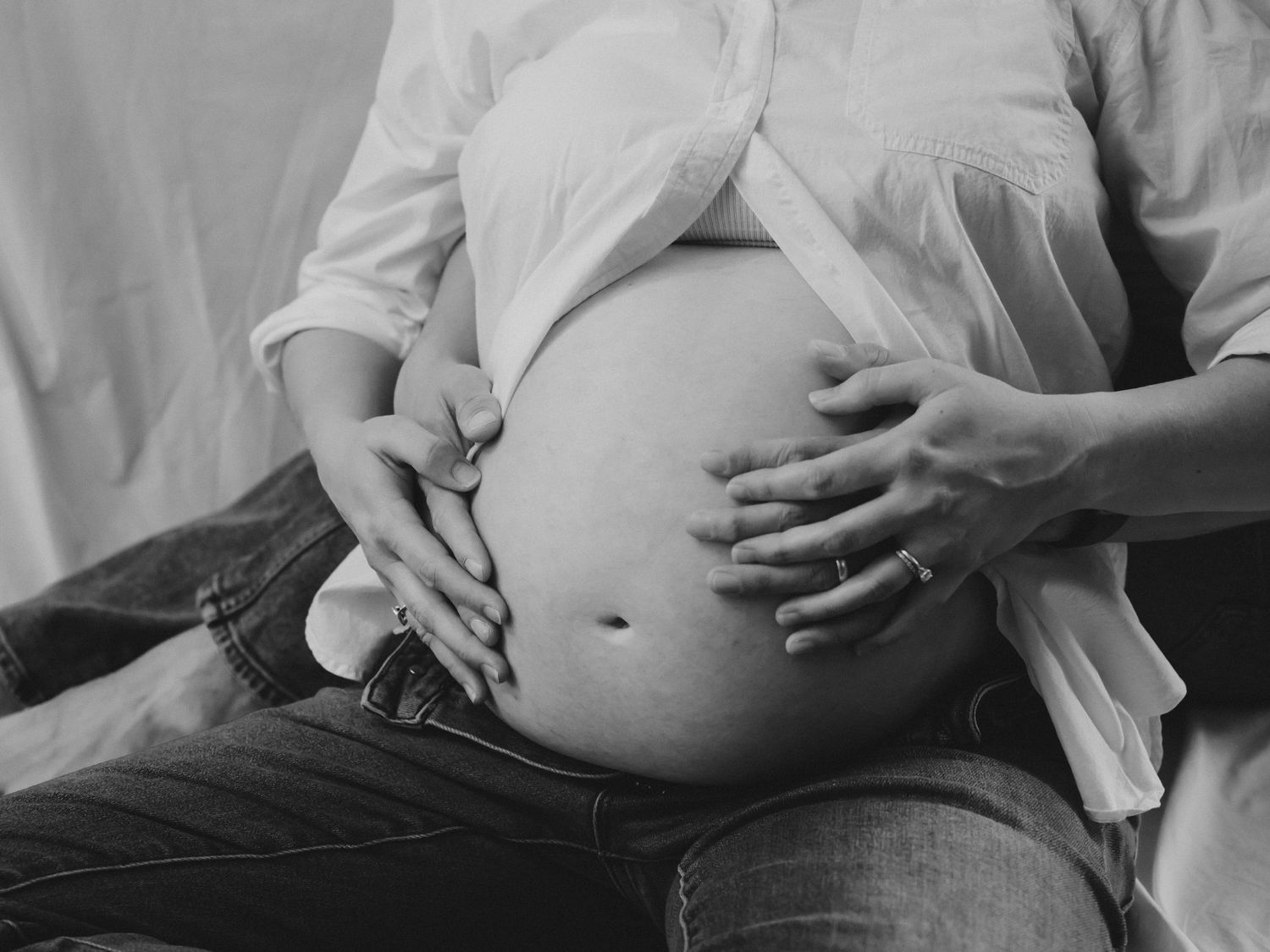 Maternity photo with the couple's hands intertwined on top of mother's belly.