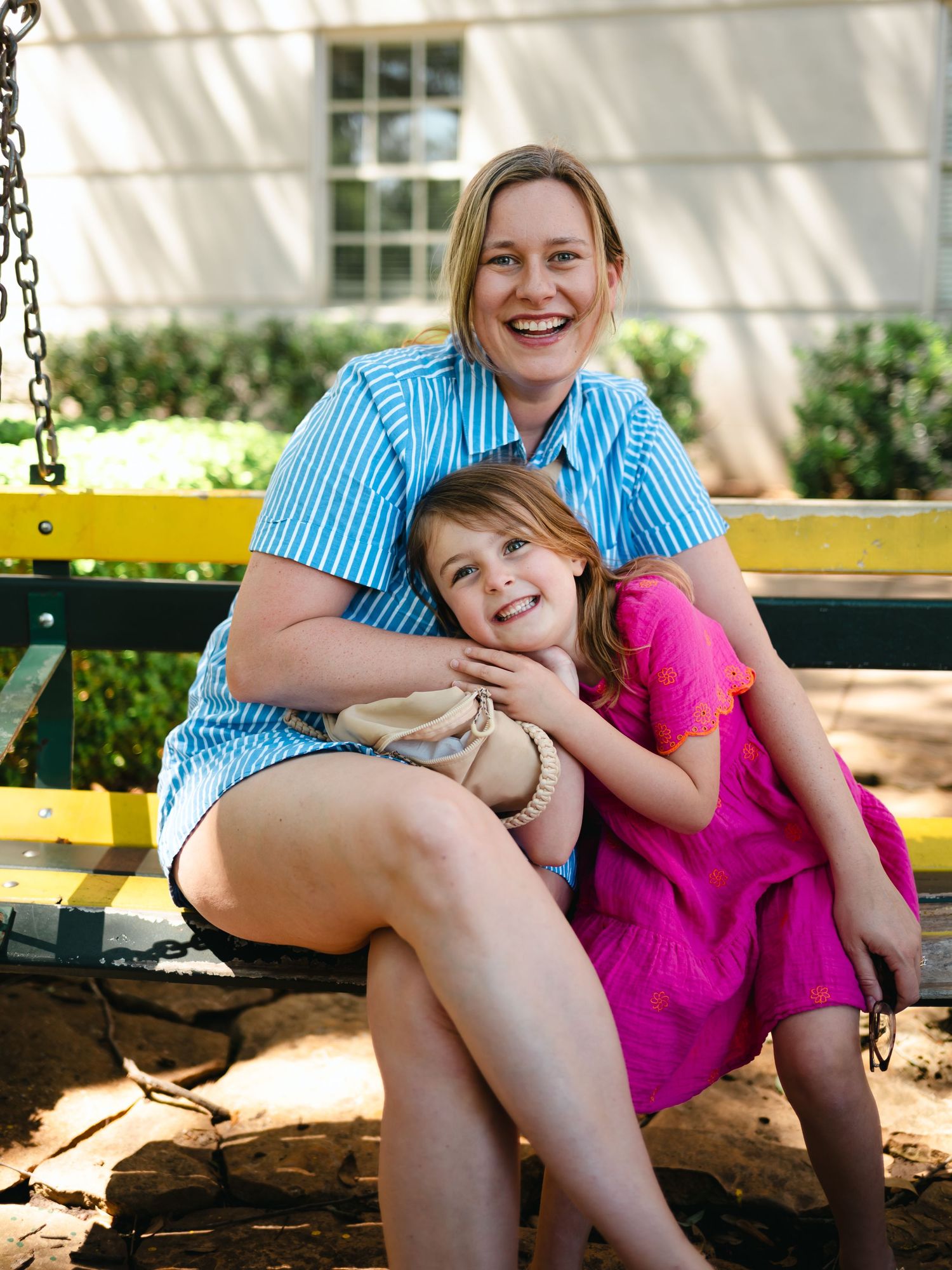 A mother and daughter smiling on a bench swing