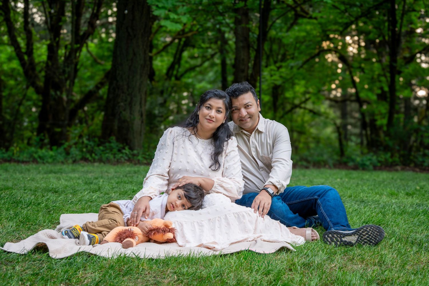 Family of three cuddling together on a blanket during a relaxed outdoor family photography session near Portland, Oregon