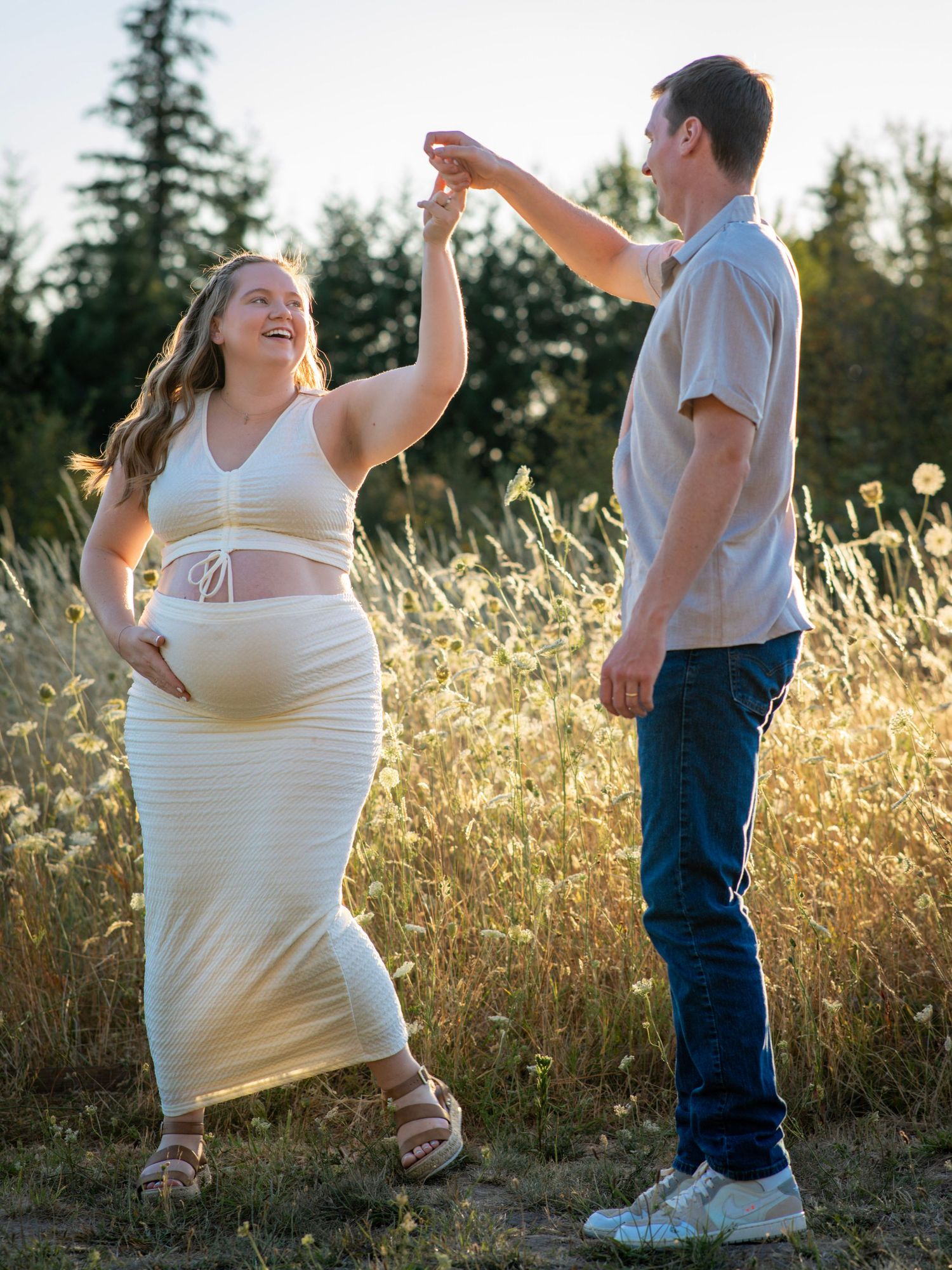 Expectant couple laughing and dancing together during a relaxed outdoor maternity session.