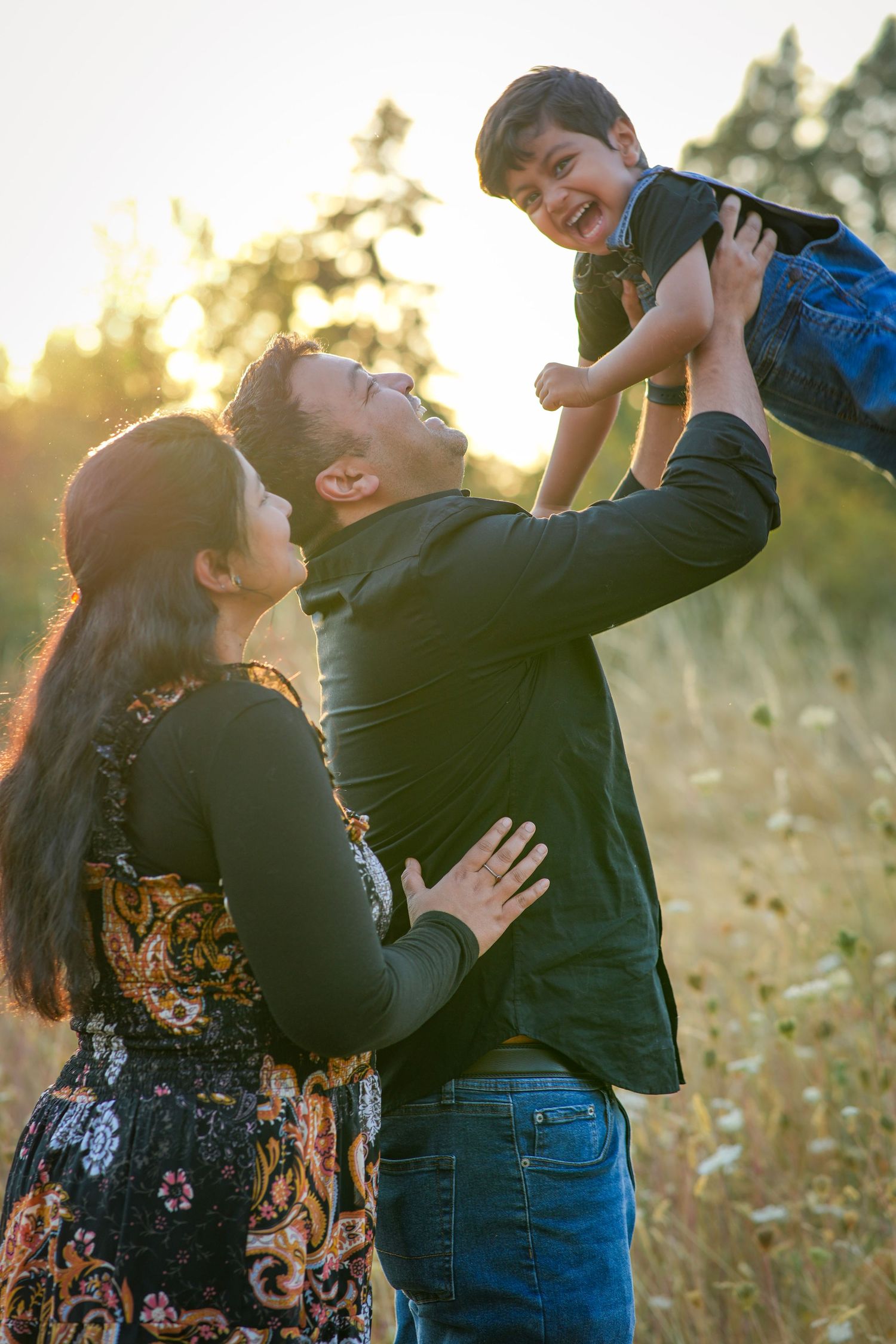Dad lifting his laughing young son into the air during a playful golden hour family photography session